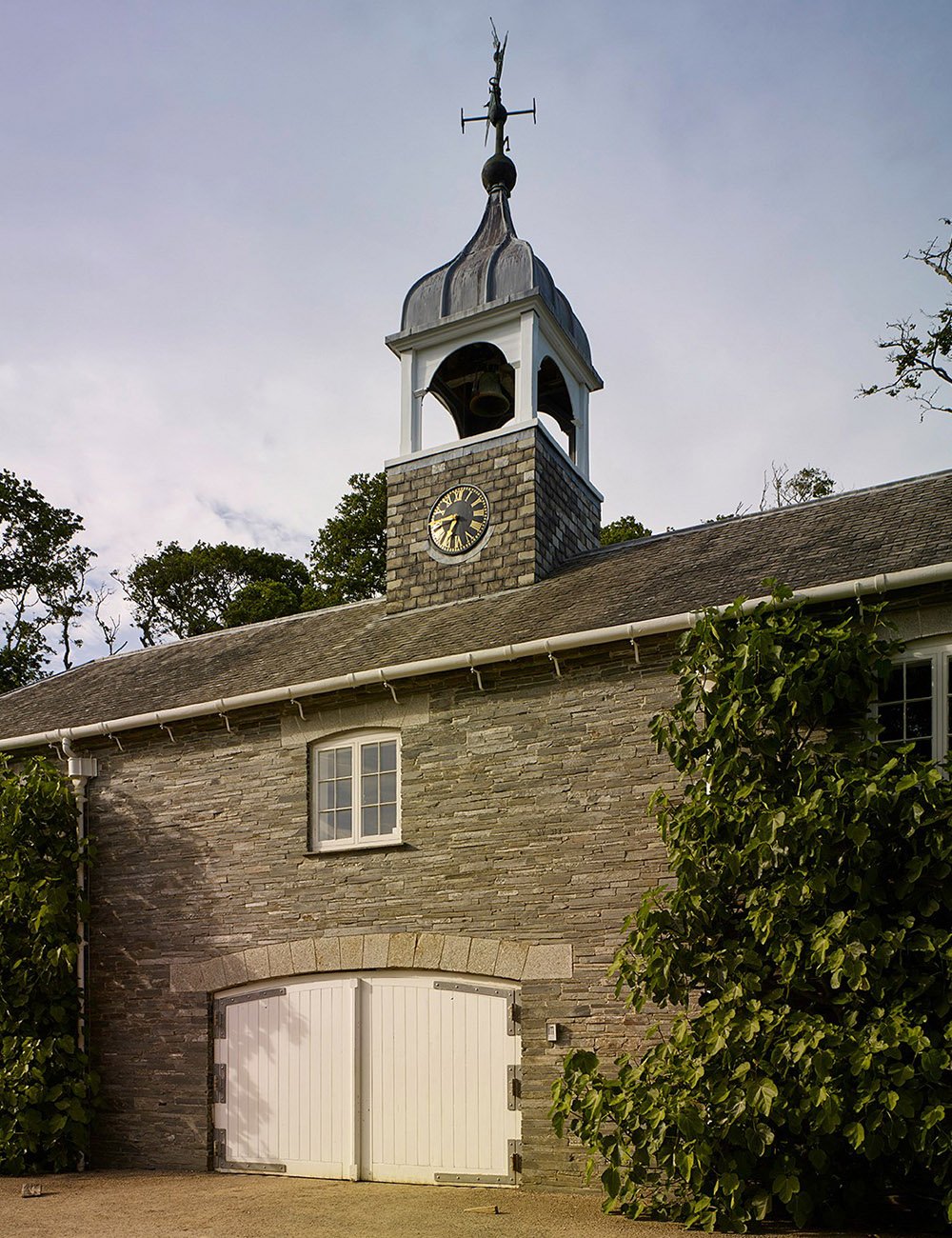 Stone garden building in Cornwall featuring a clock tower and traditional architectural detailing.