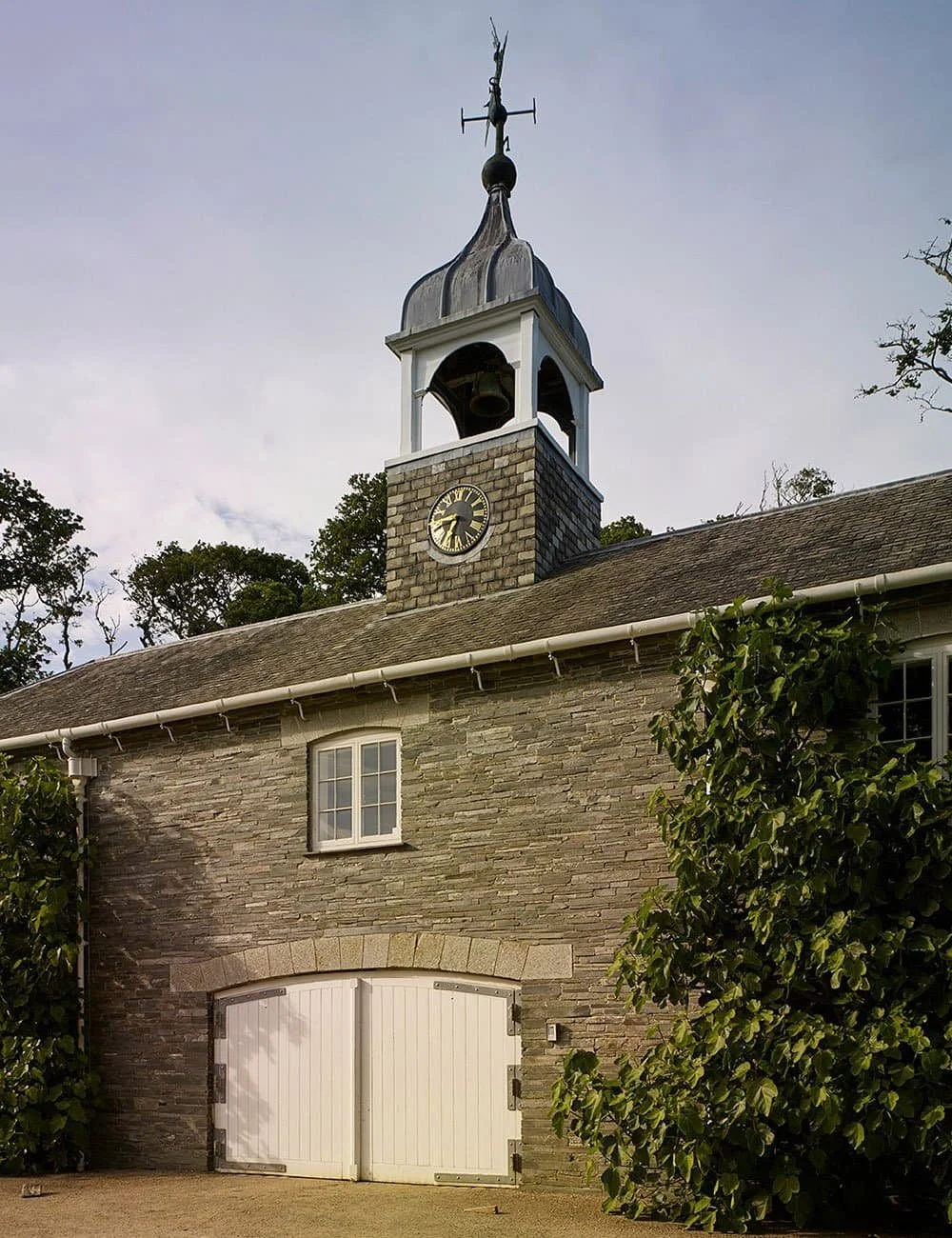 Stone garden building in Cornwall featuring a clock tower and traditional architectural detailing.