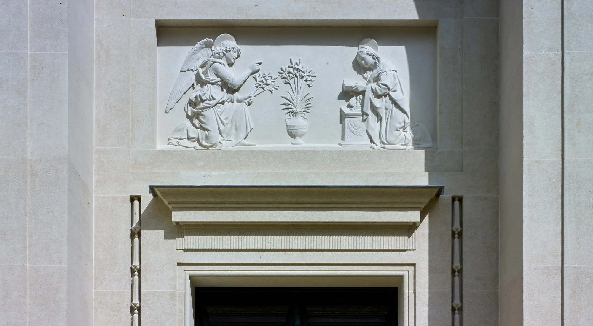 Hand-carved classical stone relief above the entrance to the Chapel of Our Lady at Williamstrip, depicting the Annunciation.