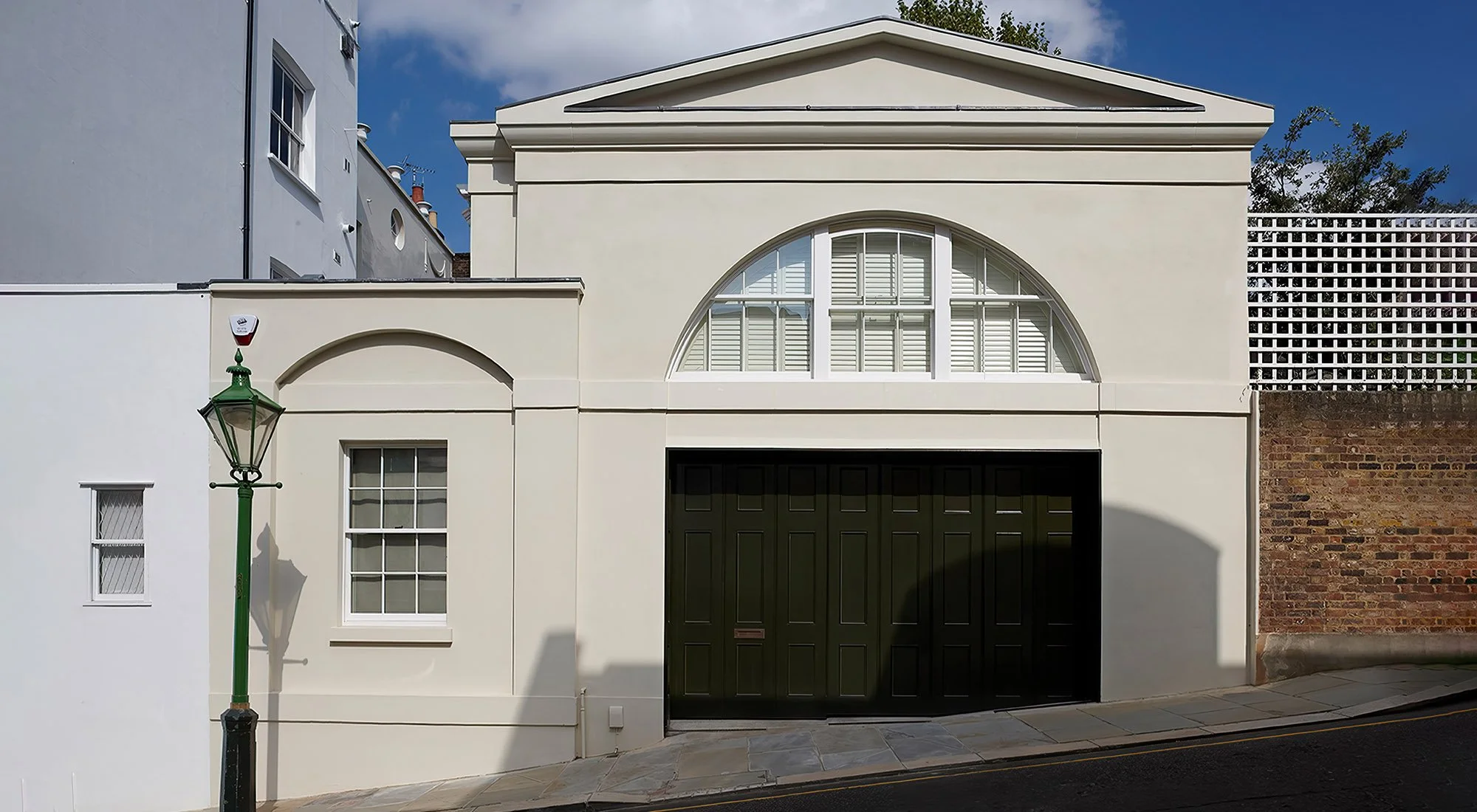 Traditional London mews house featuring classical architecture, arched glazing and rendered façade by Craig Hamilton Architects.