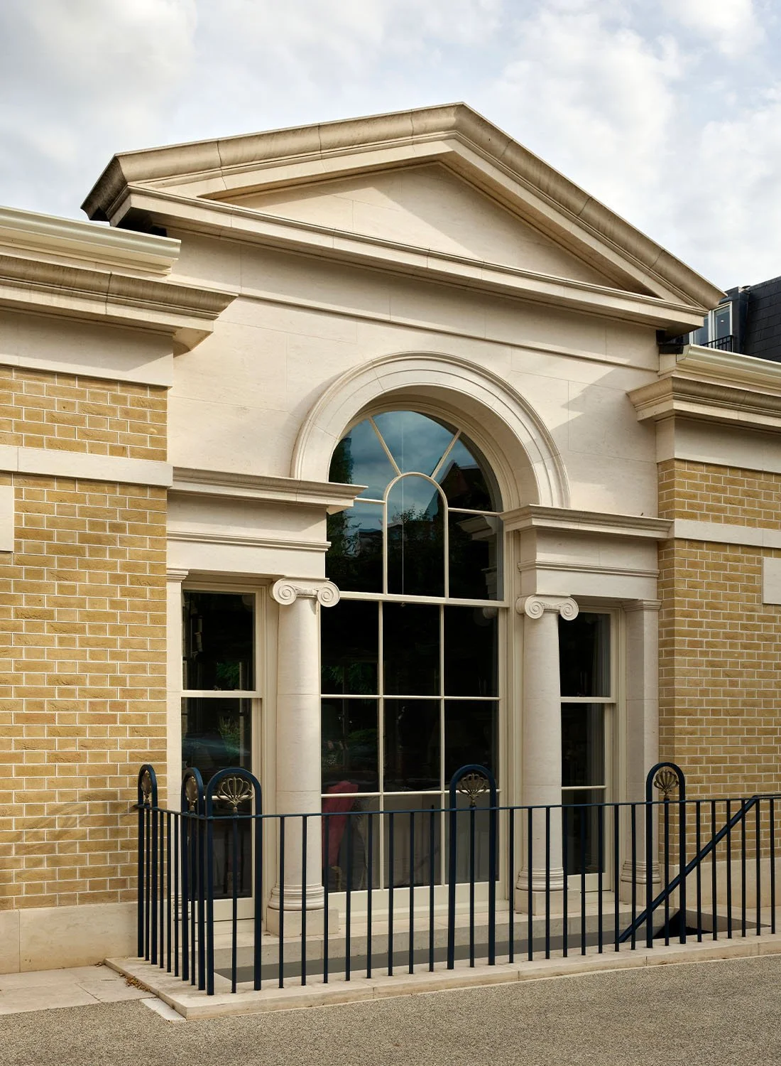 Classically designed London courtyard house featuring a pedimented façade, arched window and stone columns.