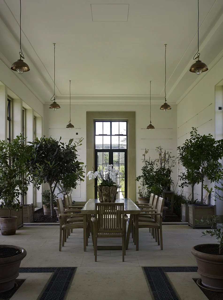 Interior seating area within the orangery featuring tall windows and views across the estate landscape.