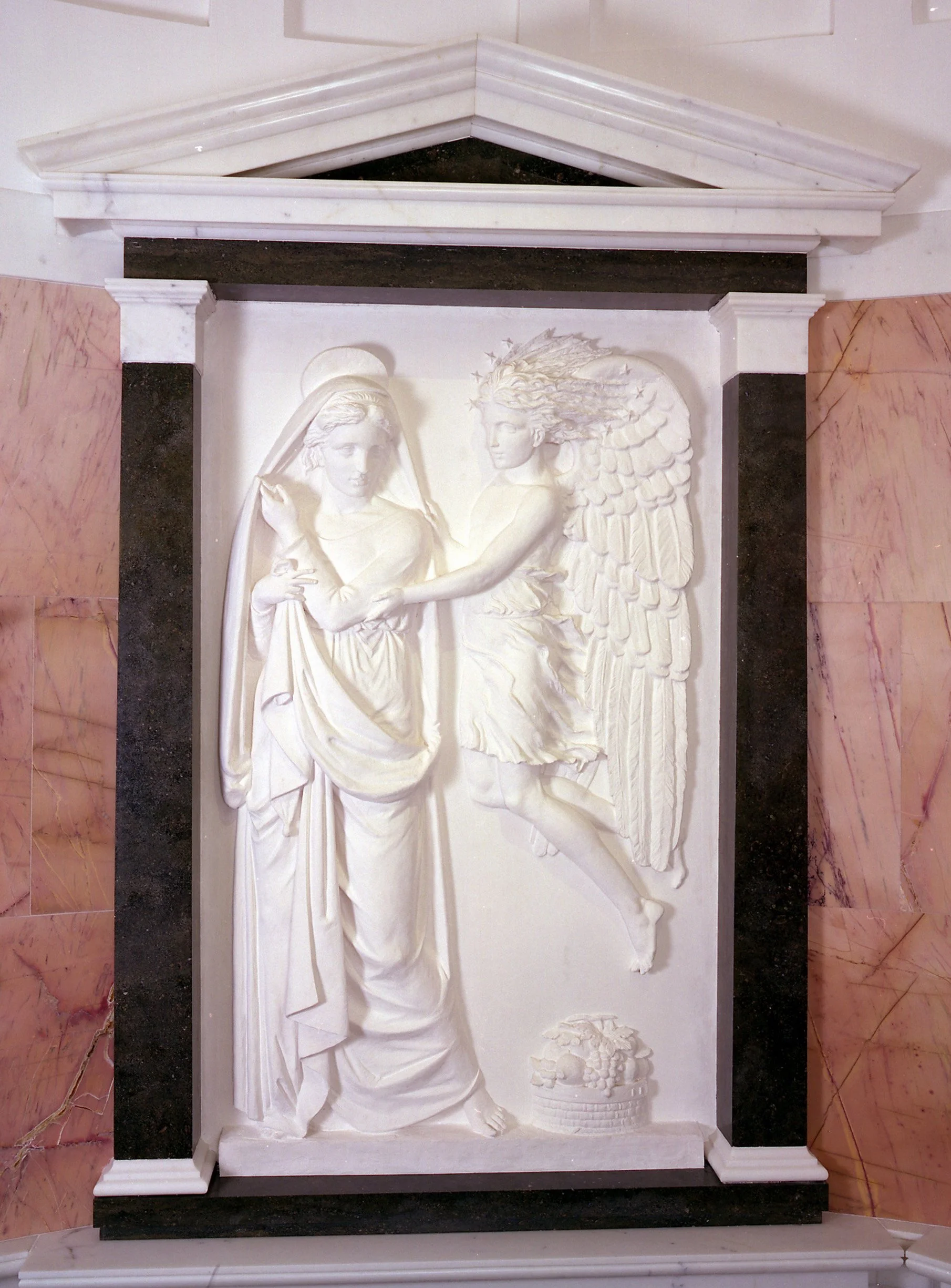 Marble angel relief within the chapel interior, framed by classical architectural detailing and coloured stone surrounds.