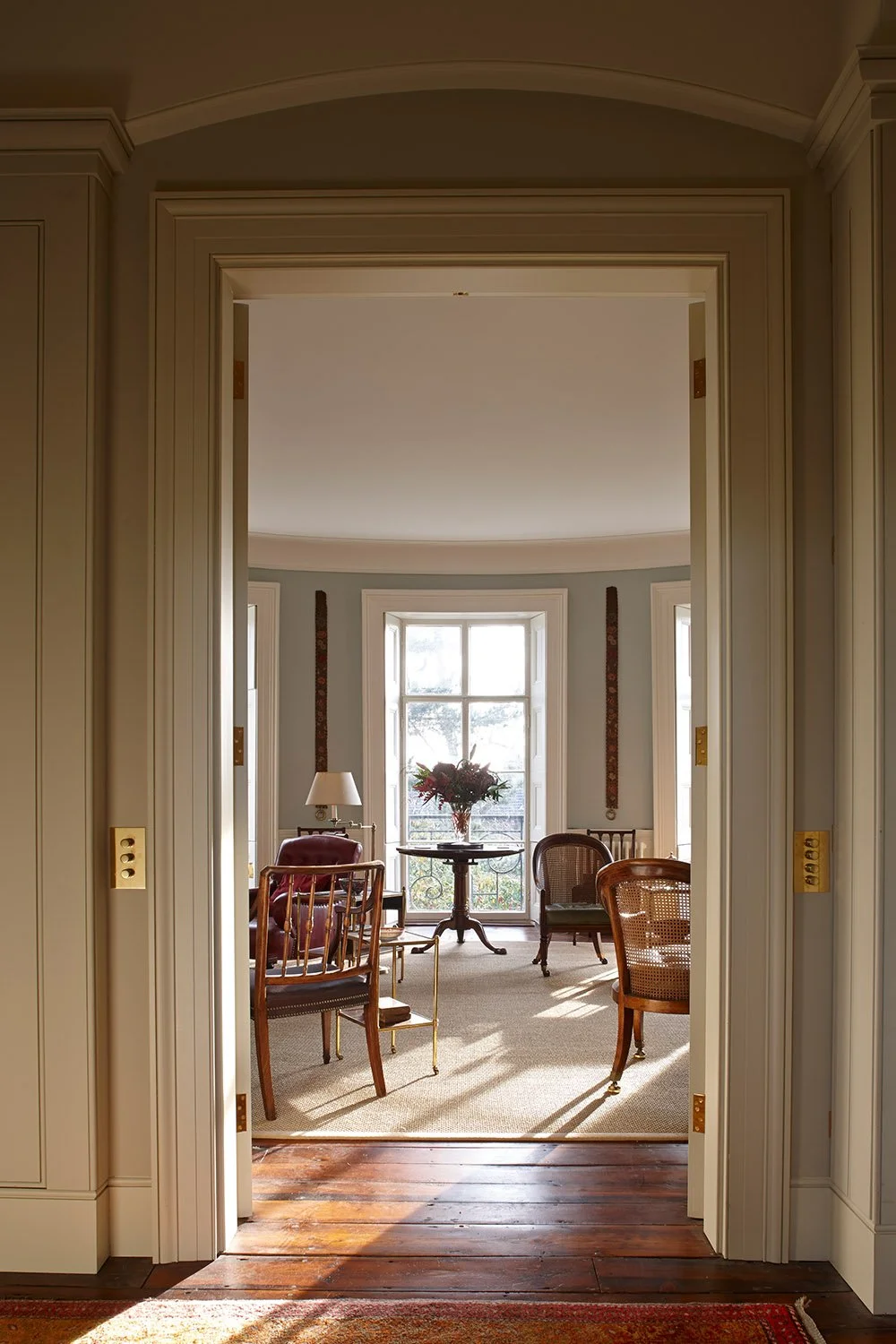 View through interconnecting reception rooms within a historic London apartment, highlighting classical proportions and natural light.