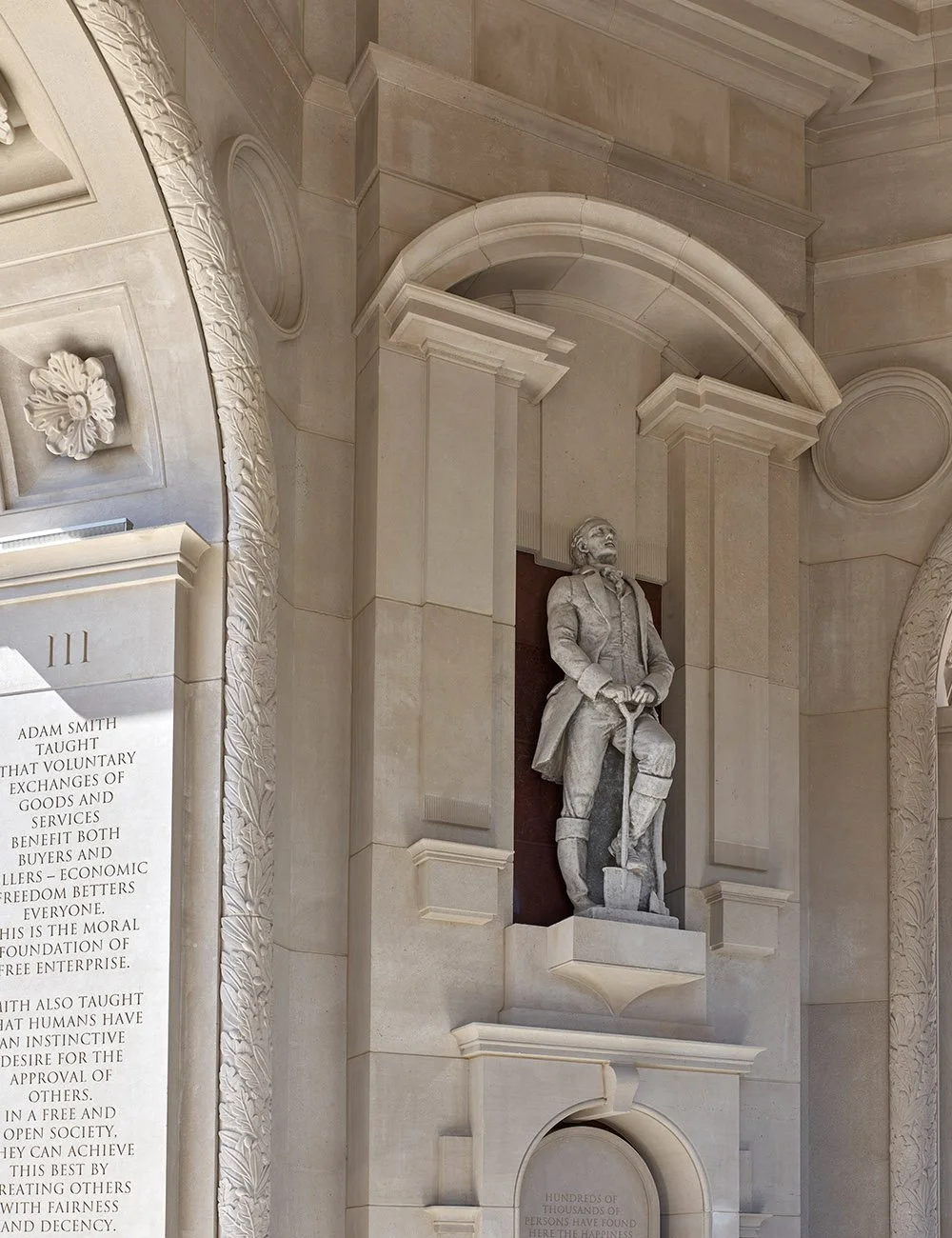 Classical stone statue set within an arched niche at The Campanile in Dallas, framed by carved limestone detailing and monumental architectural elements.