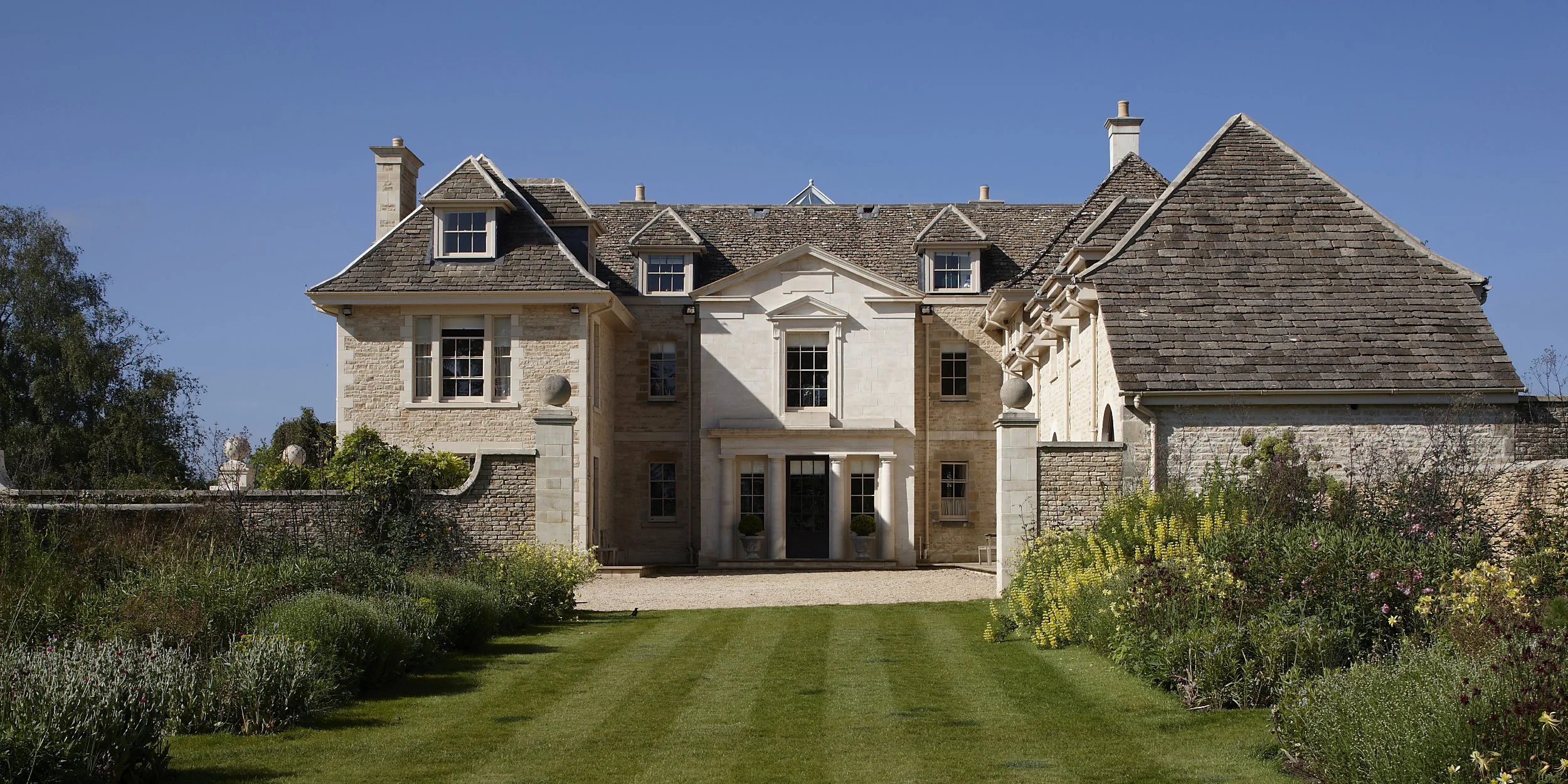 Classical Cotswolds country house designed by Craig Hamilton Architects with limestone façade, formal entrance court and landscaped gardens