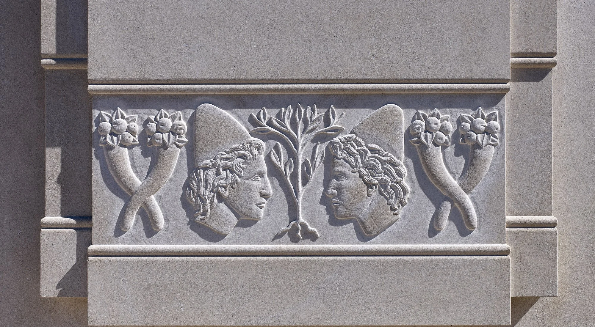Carved stone relief depicting classical figures and ornamental motifs on The Campanile in Dallas, Texas.