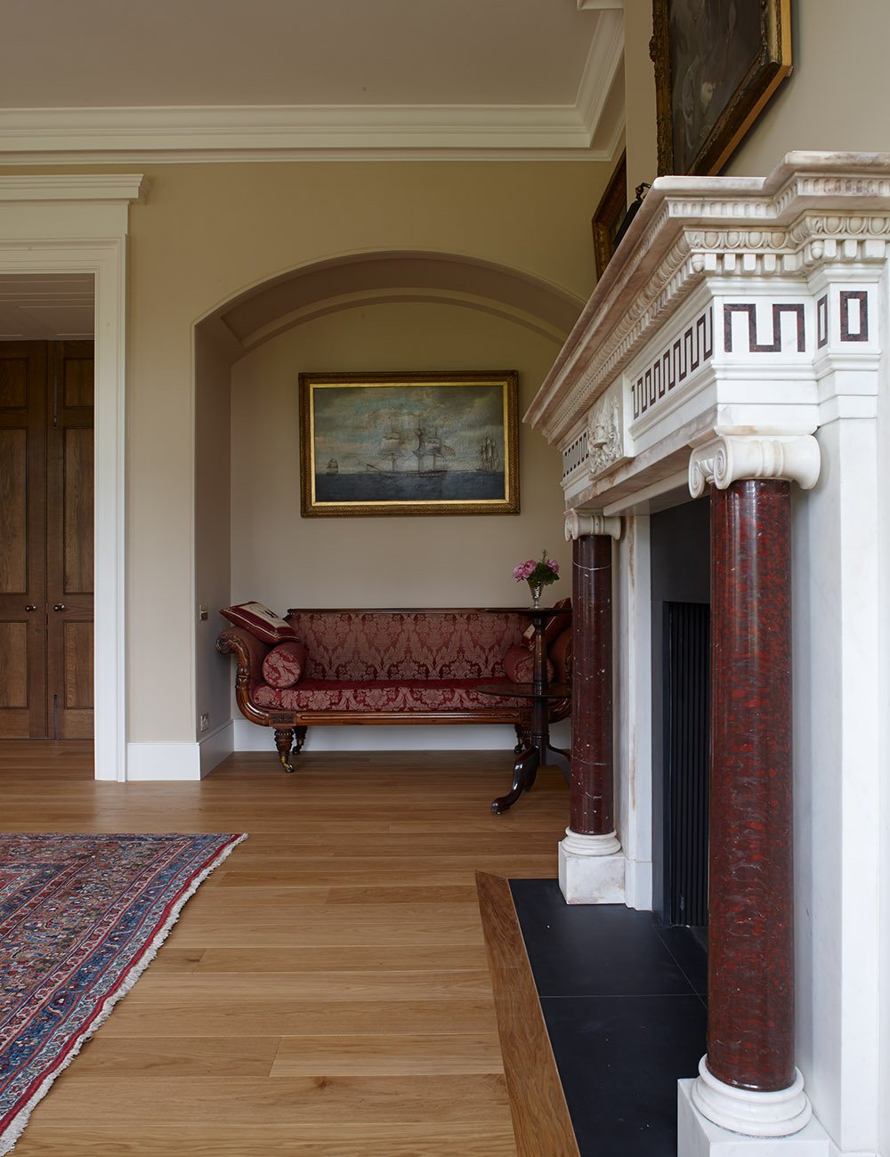 Decorative classical fireplace with marble columns, oak flooring and traditional country house interior detailing