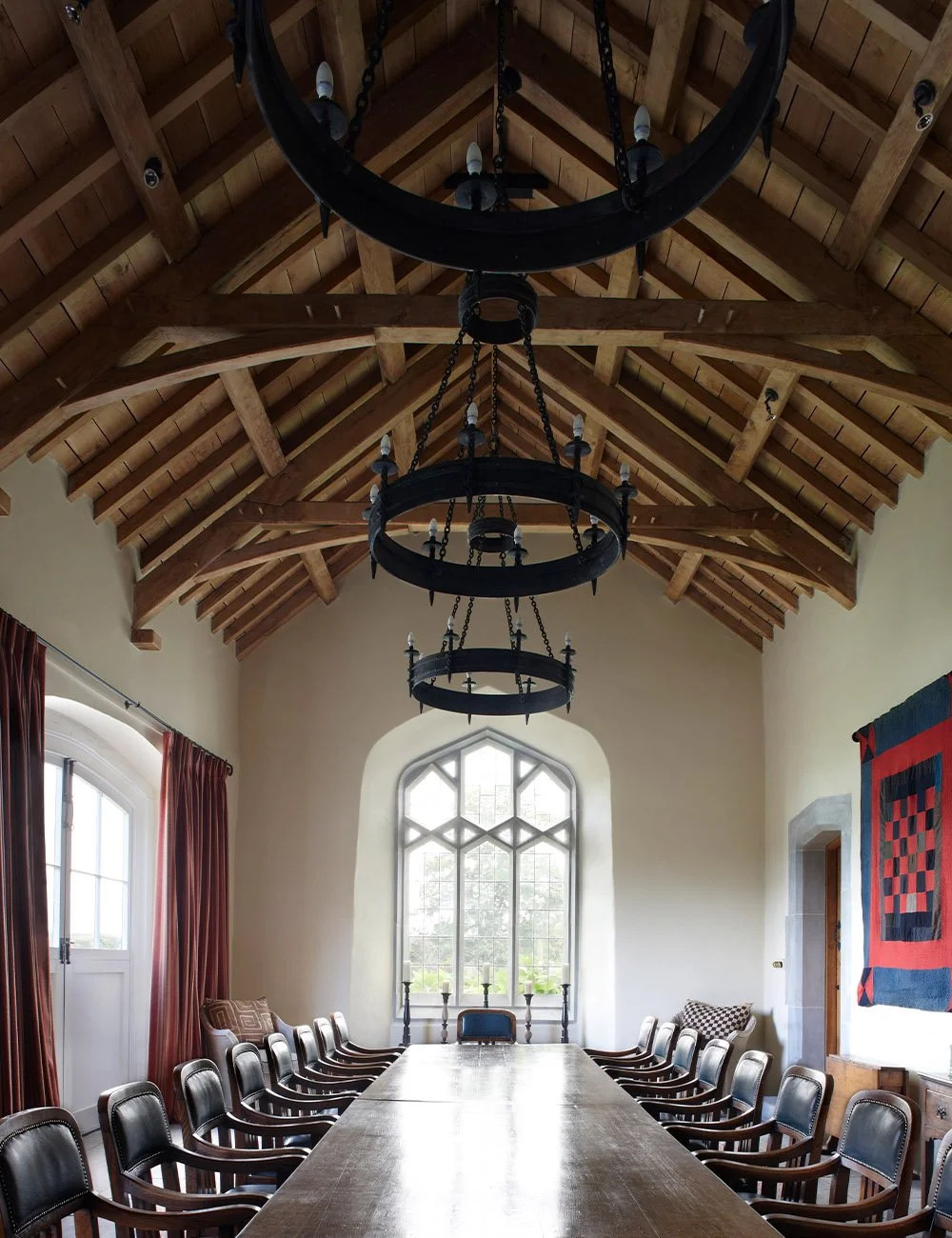 Traditional great hall with exposed timber roof, long dining table and Gothic window at Llwynwermod.