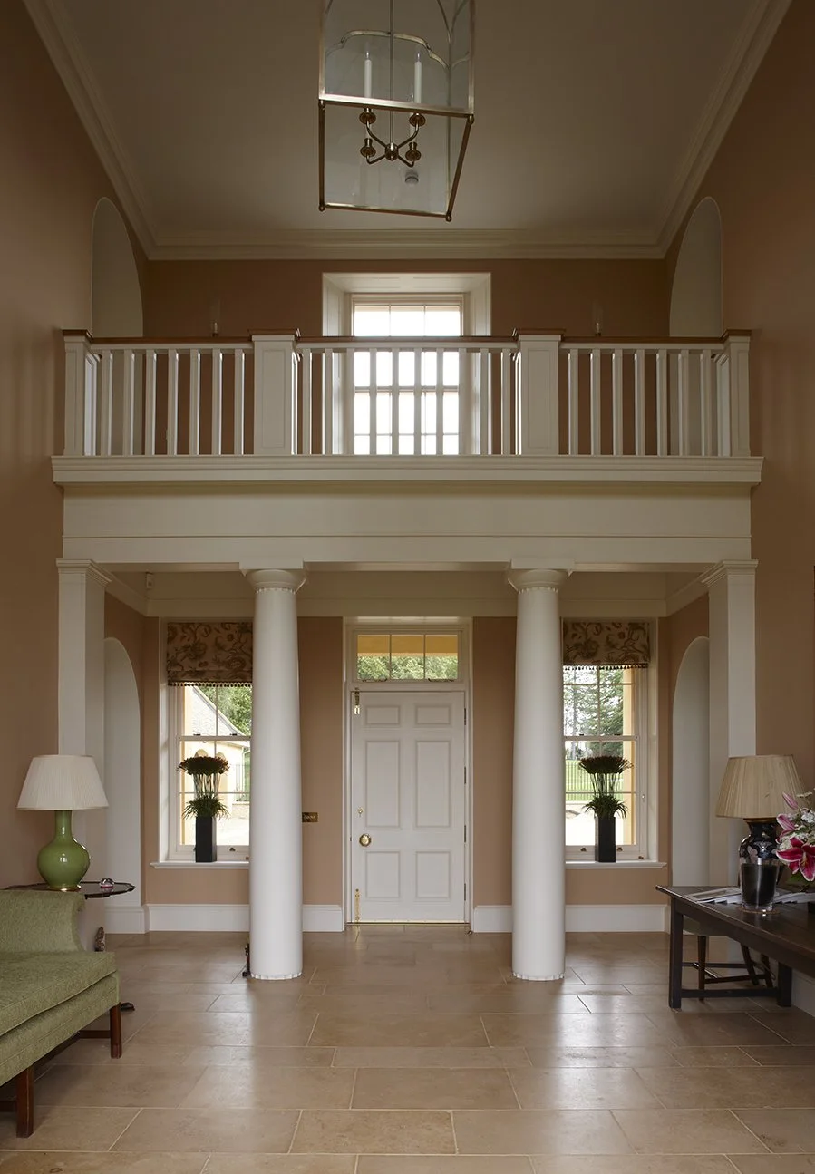 Double-height classical entrance hall with columns in Gloucestershire country house by Craig Hamilton Architects