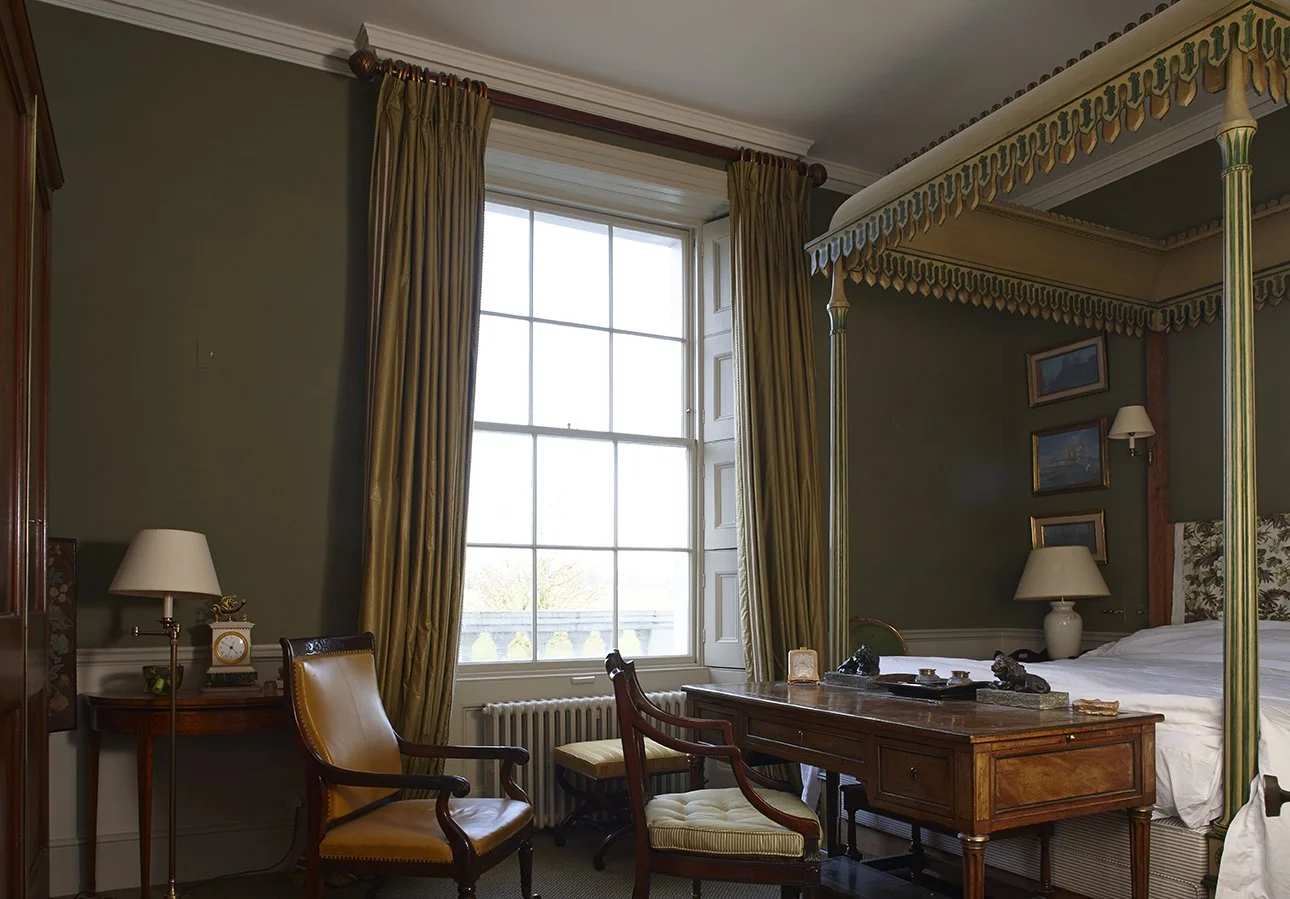 Principal bedroom within a historic London apartment featuring restored period features, classical fireplace and tall sash windows.