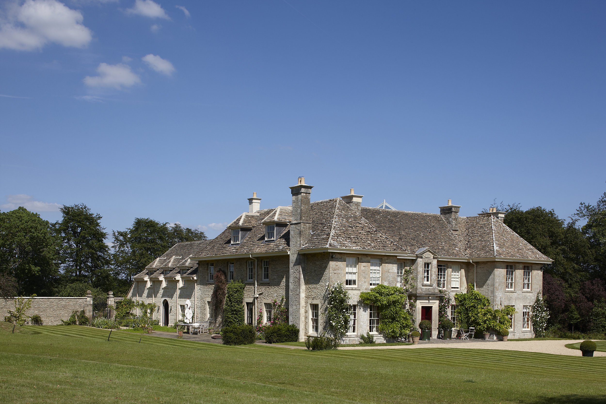 Classical limestone country house with formal lawn and traditional English country architecture in the Cotswolds by Craig Hamilton Architects