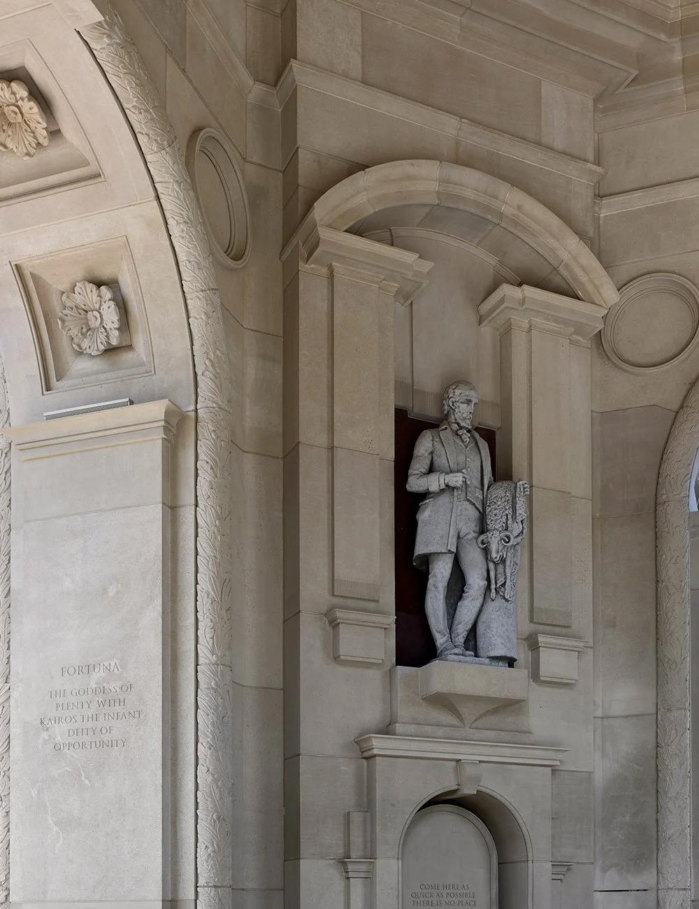 Classical statue framed by carved stone arches and architectural detailing at The Campanile in Dallas.