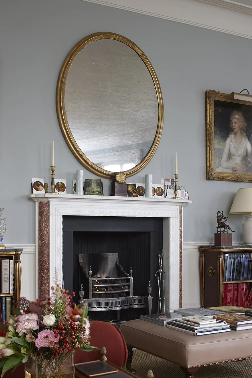 Classical fireplace and chimneypiece within a historic London apartment featuring period furnishings and restored architectural detailing.