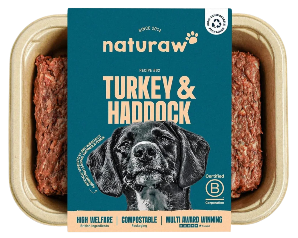 Canned dog food with a label reading 'Naturaw Turkey & Haddock.' The label features a black and white illustration of a dog, details about the product such as 'High Welfare,' 'Compostable Packaging,' and 'Multi Award Winning,' and symbols indicating British ingredients, certification, and recycling.