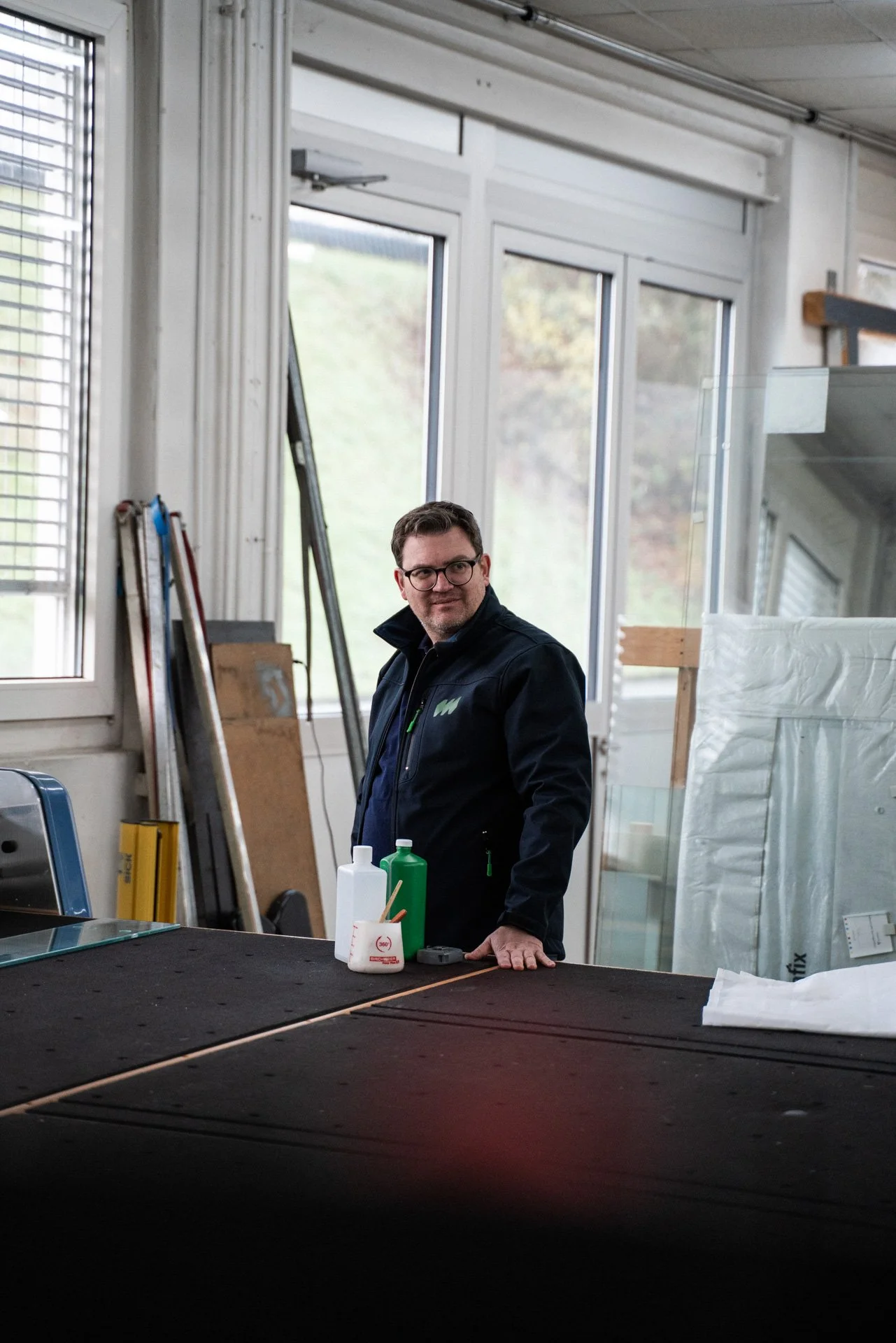 Mann steht vor einer Werkbank und trägt eine Brille