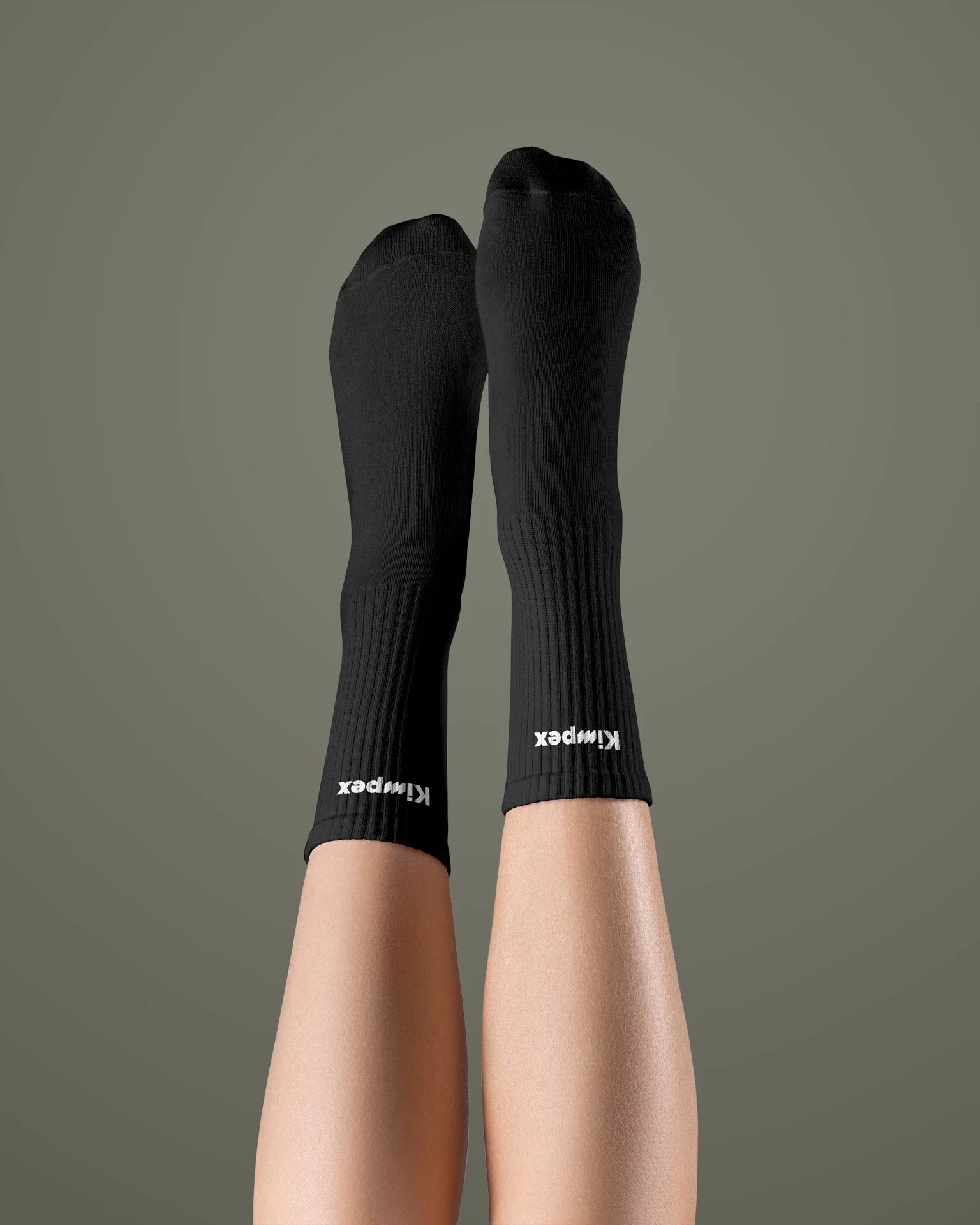 Beine mit schwarzen Kniestrümpfen mit weissem Kimpex-Logo, gegen grauen Hintergrund.
