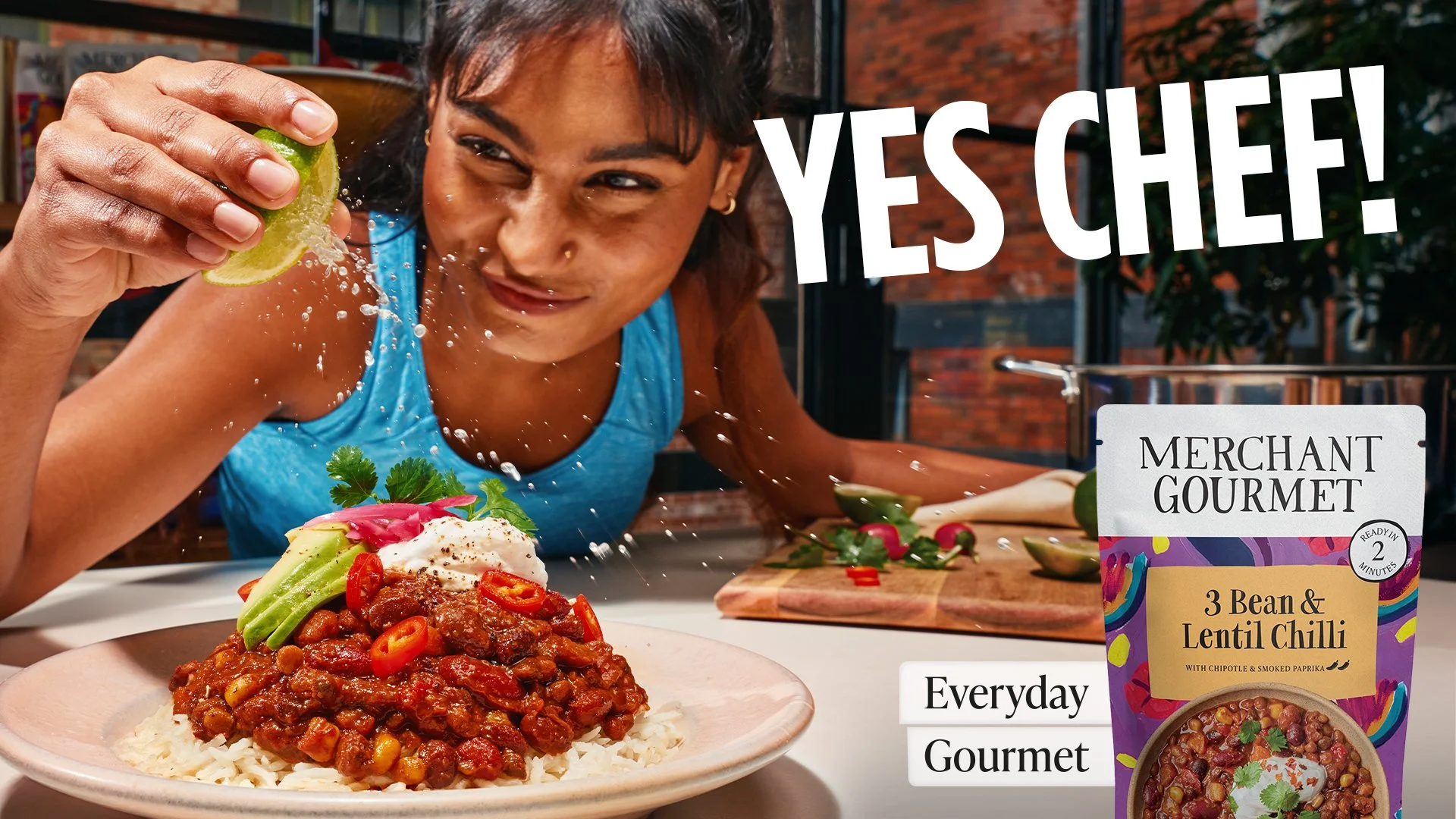 Woman pouring lime over a dish of chili, rice, and vegetables, with a packet of lentil chili seasoning on the table