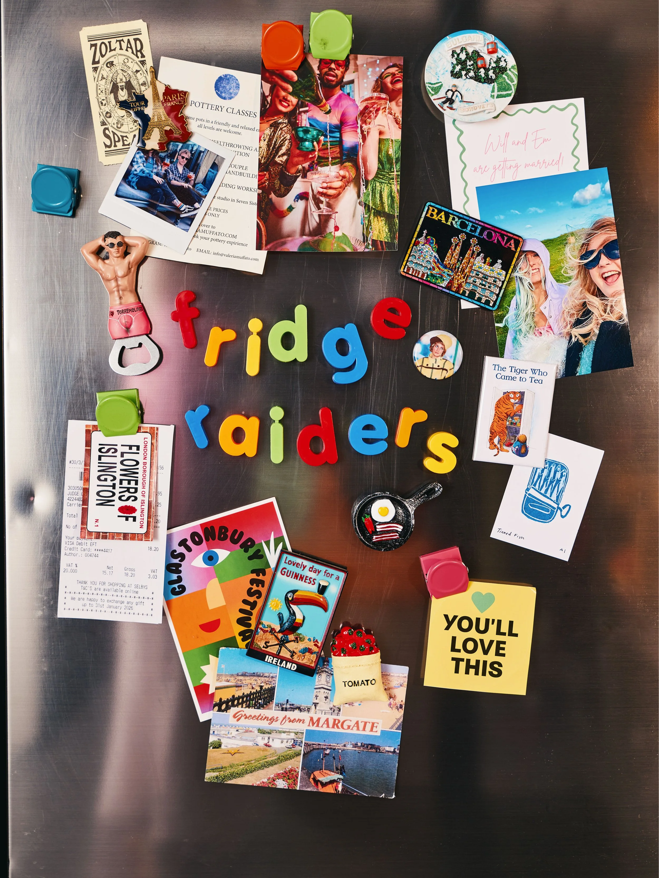 A collection of souvenirs, photographs, and memorabilia on a metallic surface. Items include colorful fridge magnets spelling 'fridge', 'rider', and other words, a travel ticket, postcards from Margate and Ireland, various photos of people and places