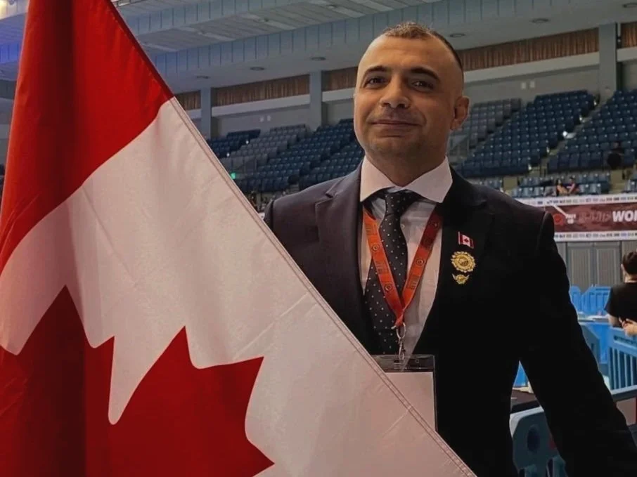 portrait of Aiden Mansour standing with a Canadian Flag
