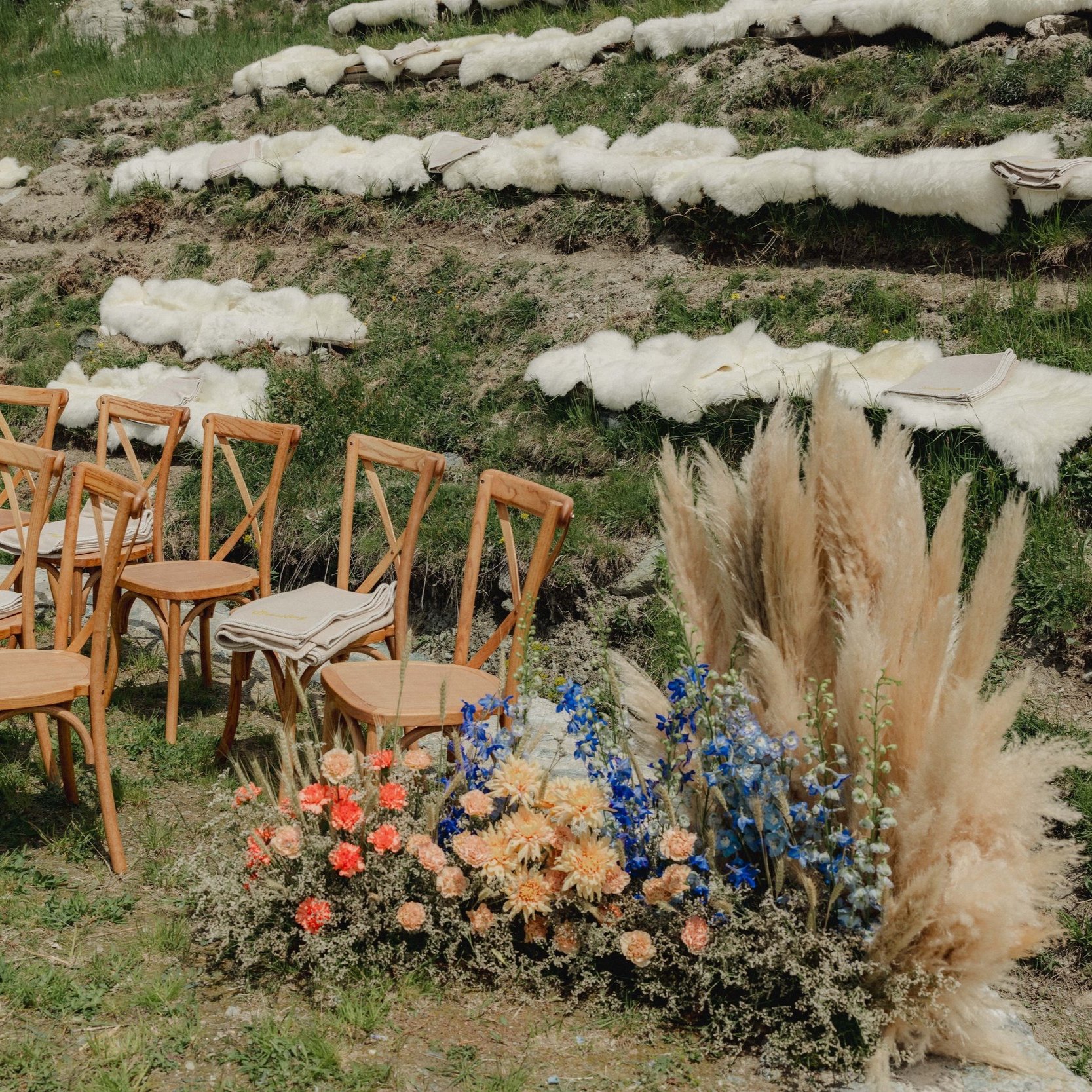 Mountain landscape with floral arrangements including pampas grass and colorful flowers, under a blue sky - created for an outstanding wedding ceremony in Zermatt.