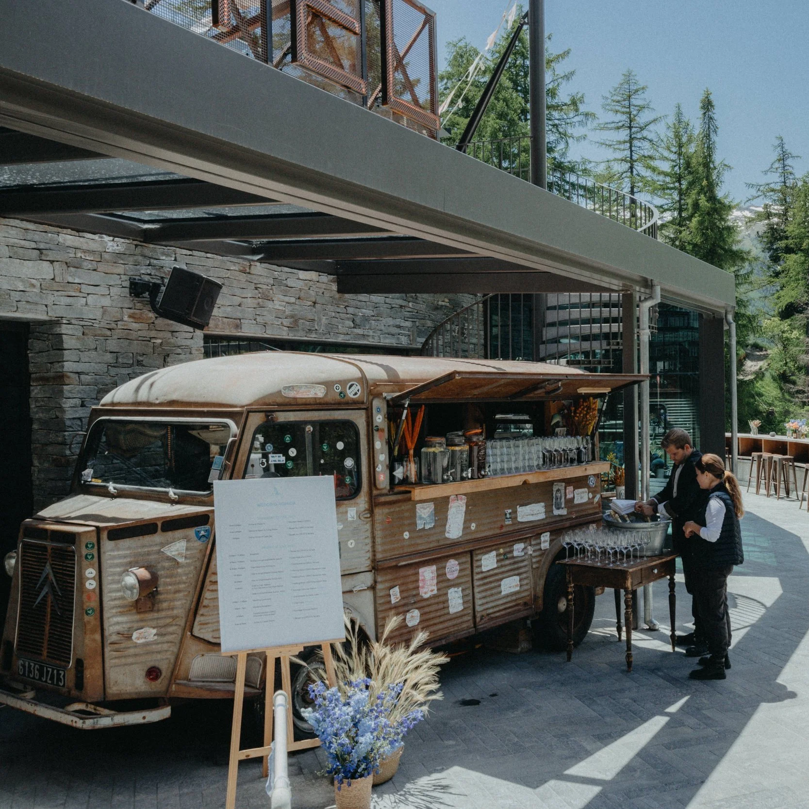 Vintage food truck with menu board and two people preparing beverages outdoors for the upcoming event in Zermatt.