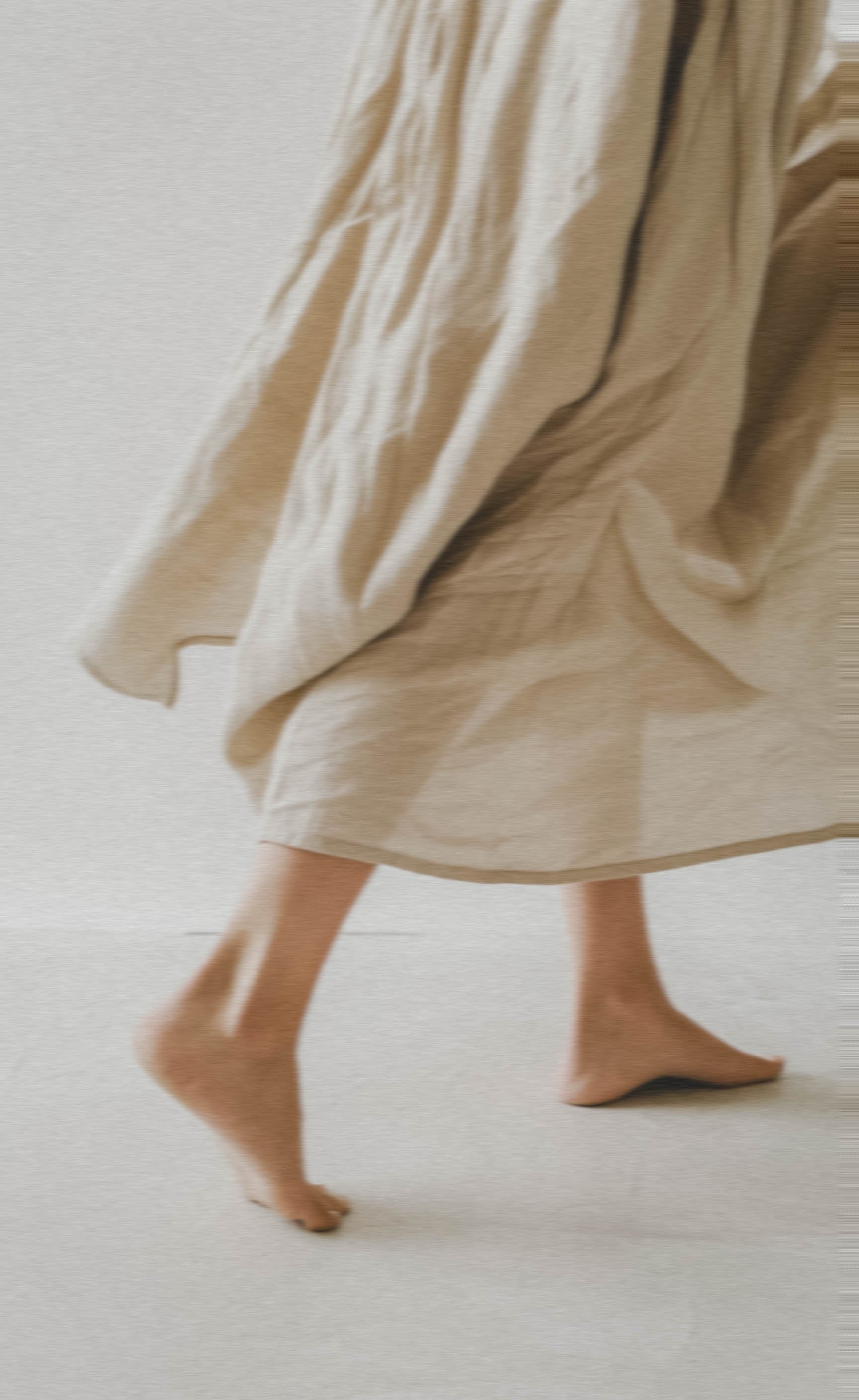 Person walking barefoot in a beige dress or robe