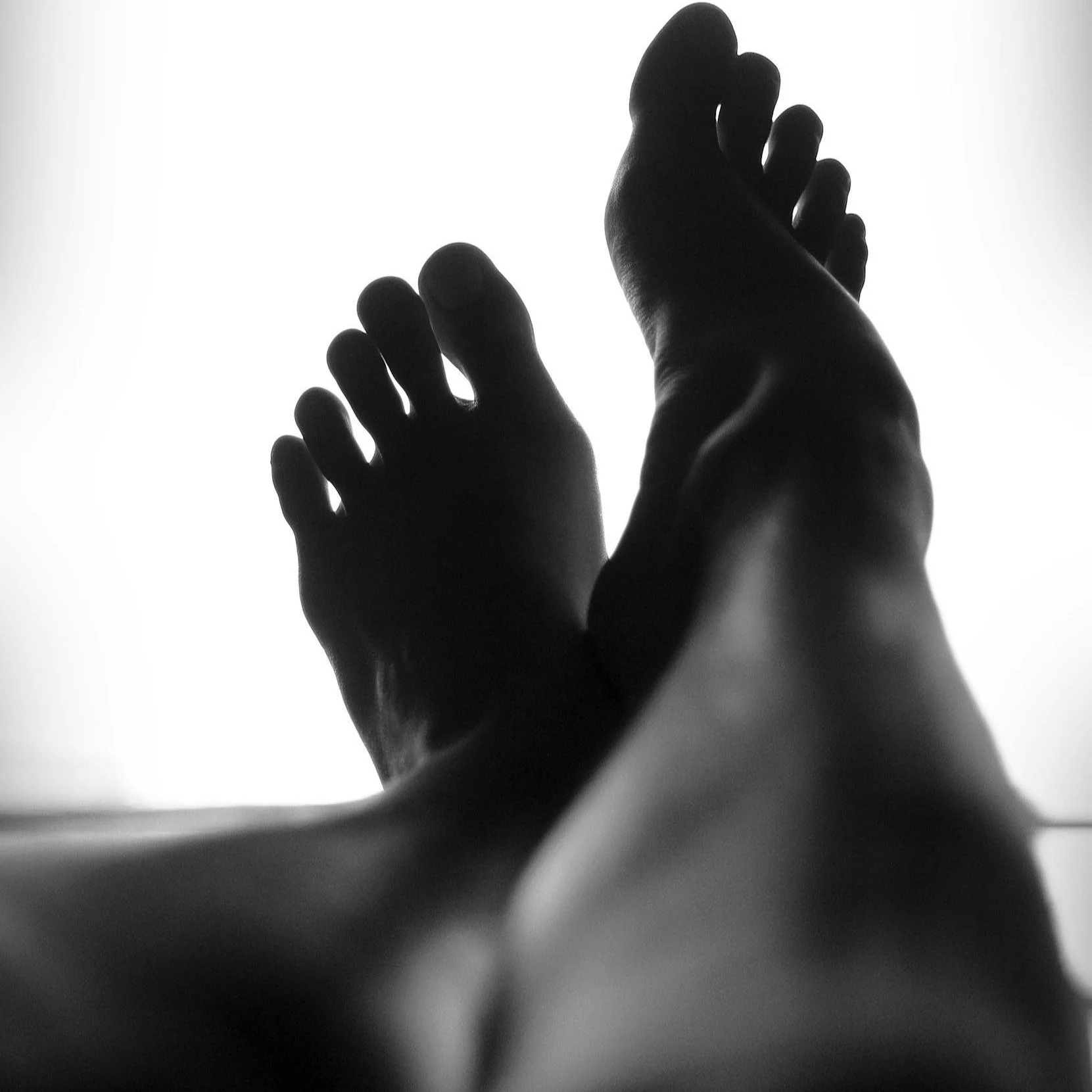 Black and white photo of reaching hands with one smaller hand in the background, seen from below.