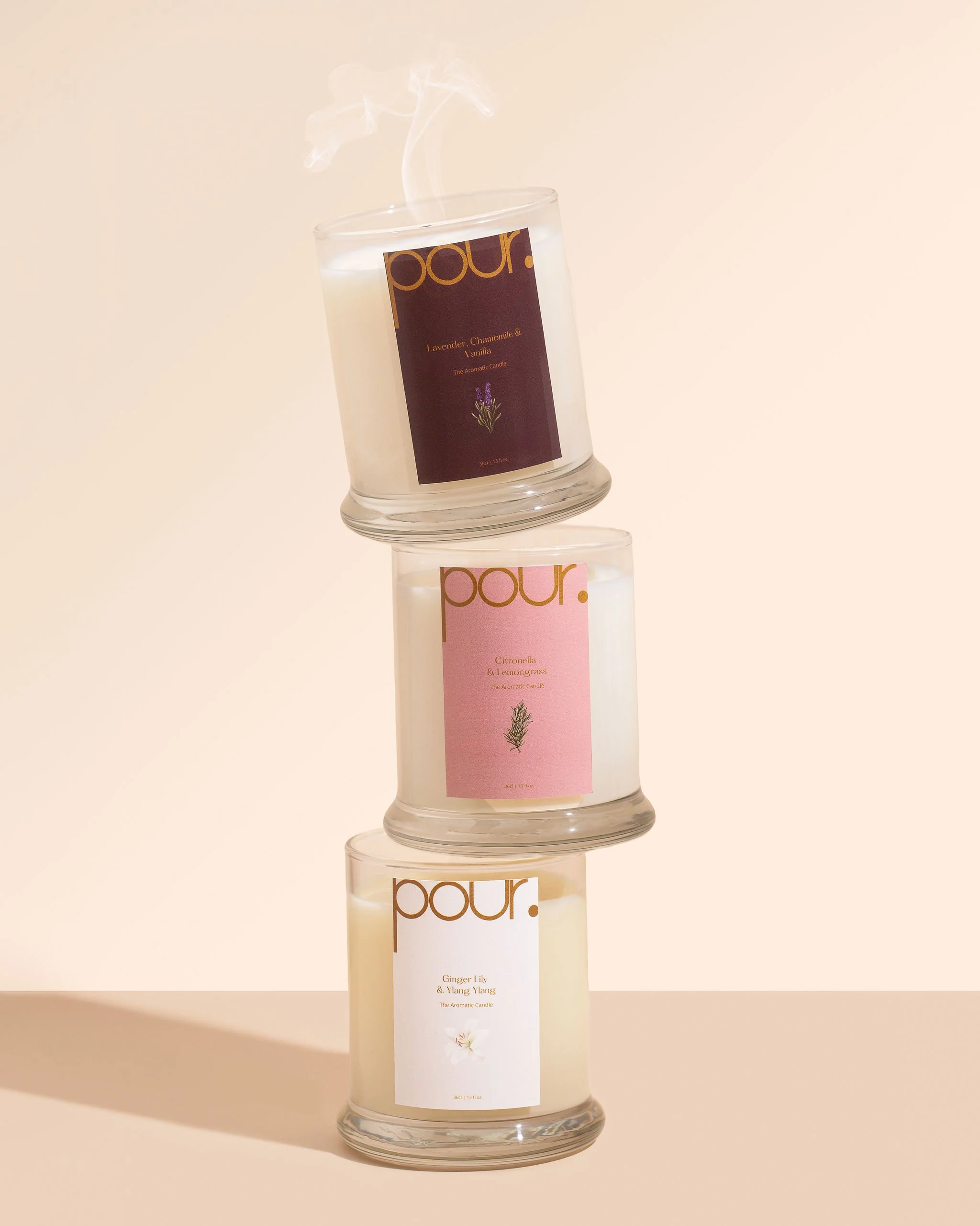 Stacked candles labeled 'Pour' with different scents: lavender and chamomile, citronella and lemongrass, ginger lily and ylang ylang.