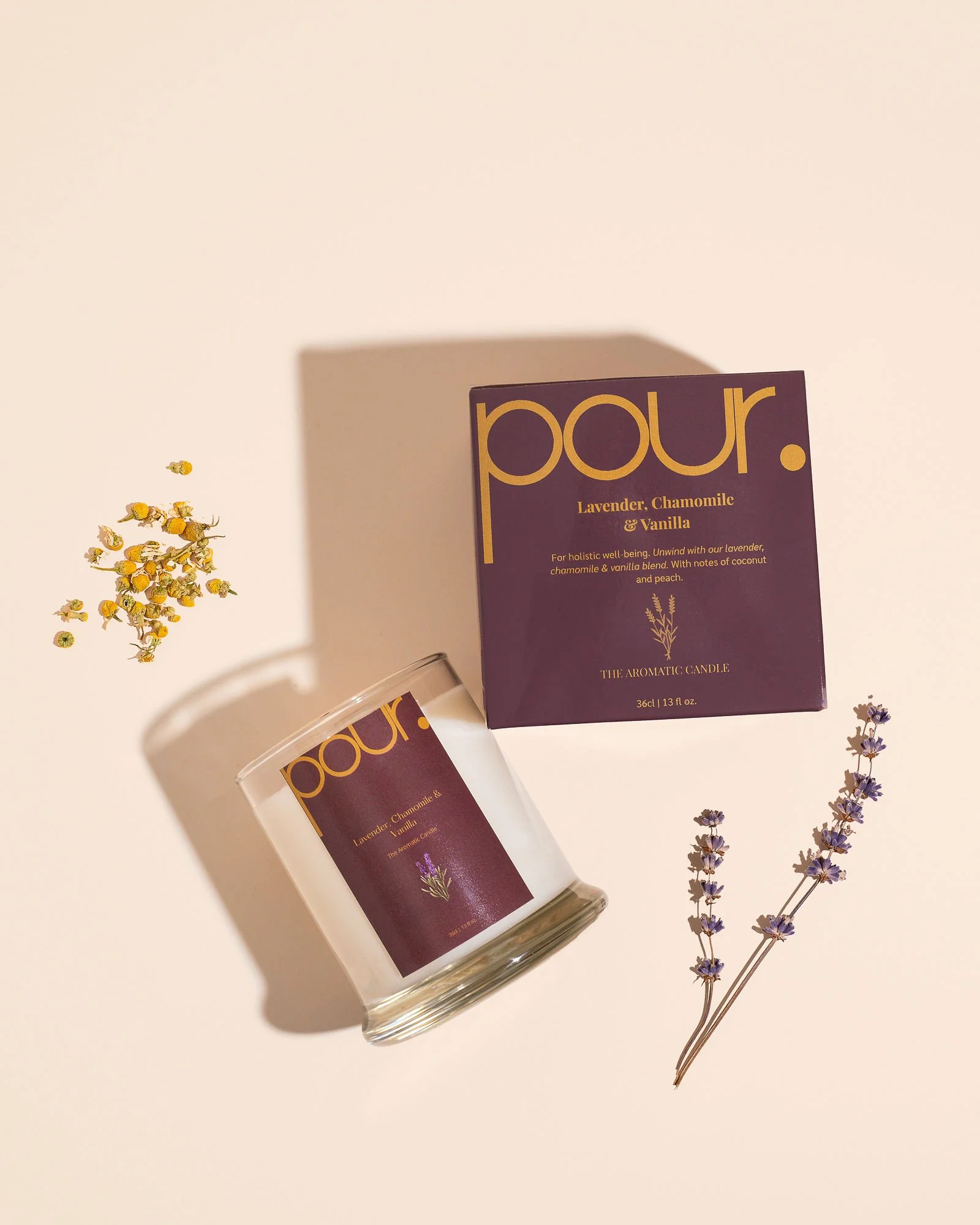 Scented candle with lavender, chamomile, and vanilla packaging, accompanied by dried lavender and chamomile flowers.