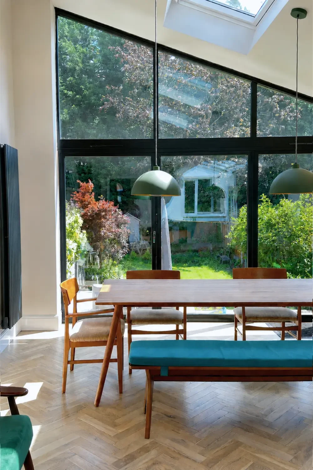 Open-plan dining area with floor-to-ceiling glazing and forest green pendants in a Birmingham extension