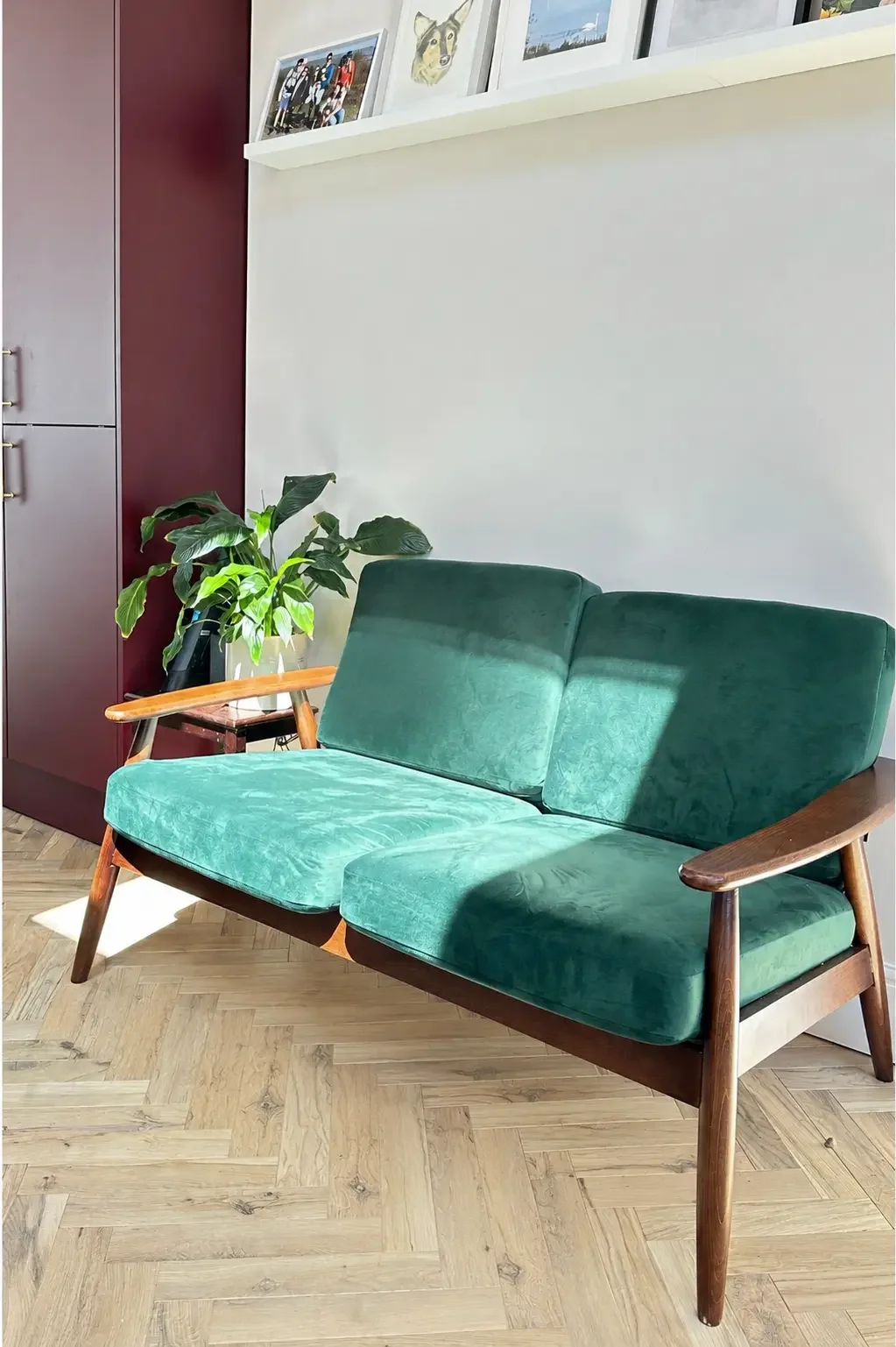 Mid-century green velvet sofa in the seating area beside morello cherry cabinetry in a Birmingham kitchen
