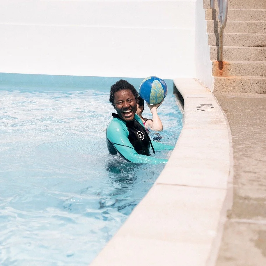 A girl smiling in a pool in the sunshine.jpeg