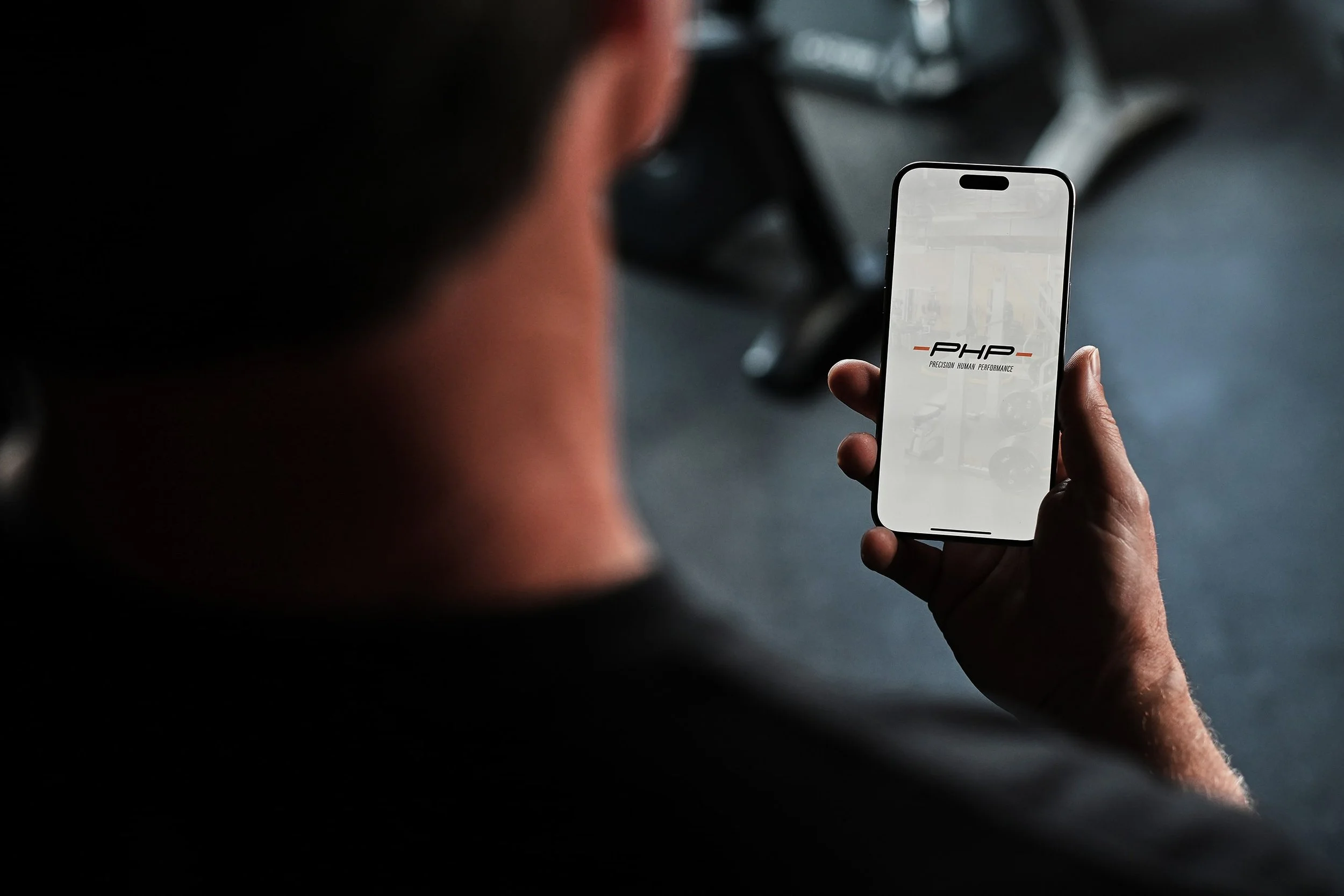 Man lifting weights at gym with a digital tablet displaying graphs and anatomical data