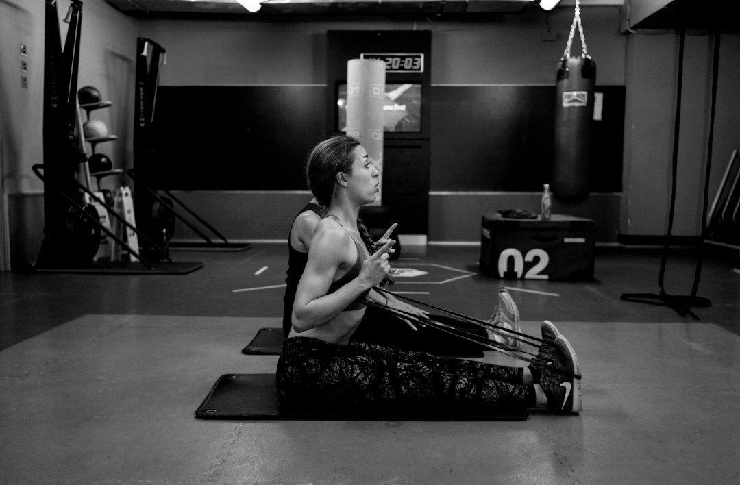 Laura, a personal trainer in Brighton teaching a female client a stretching exercise.