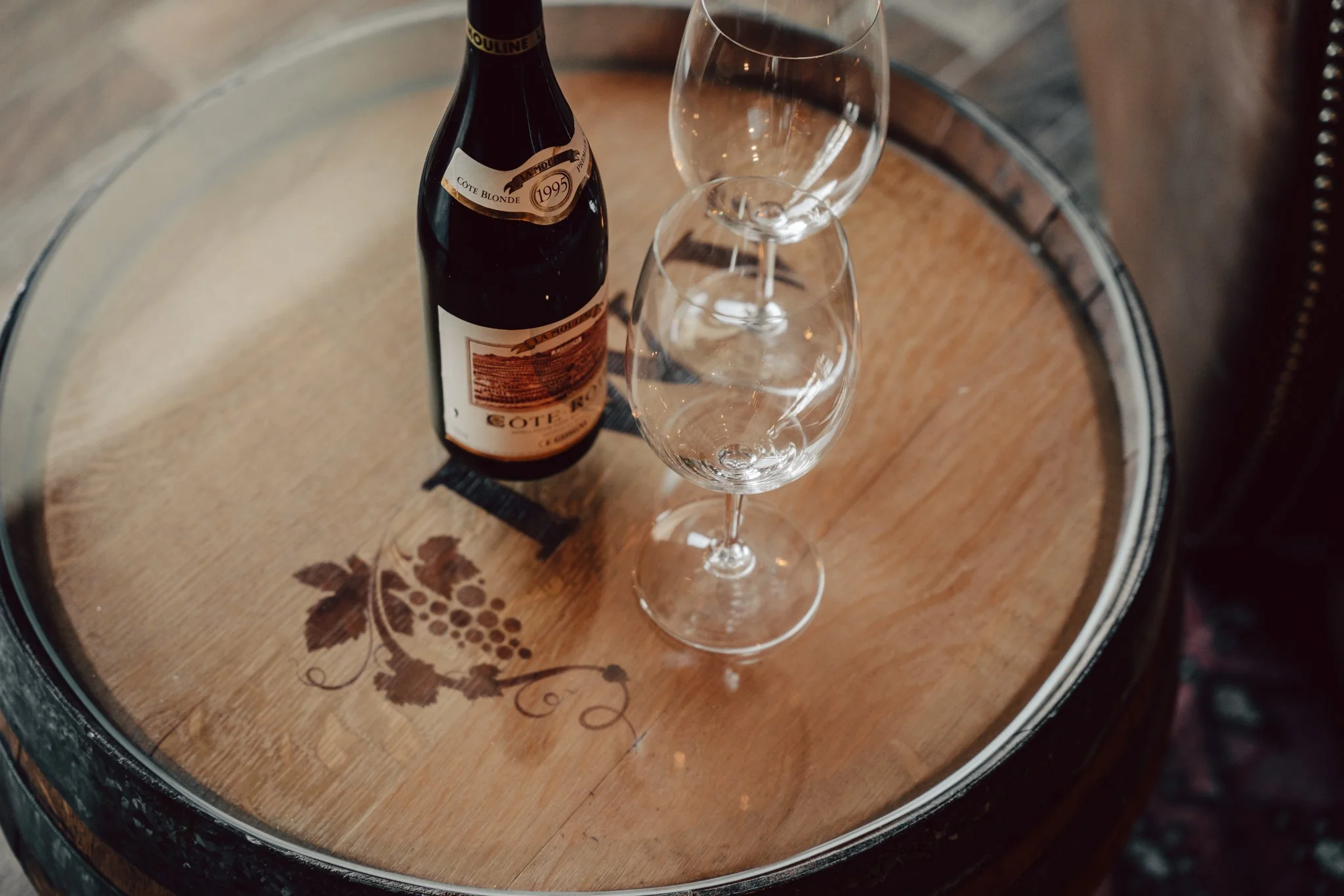 wine bottle and two glasses sitting on top of wine barrel