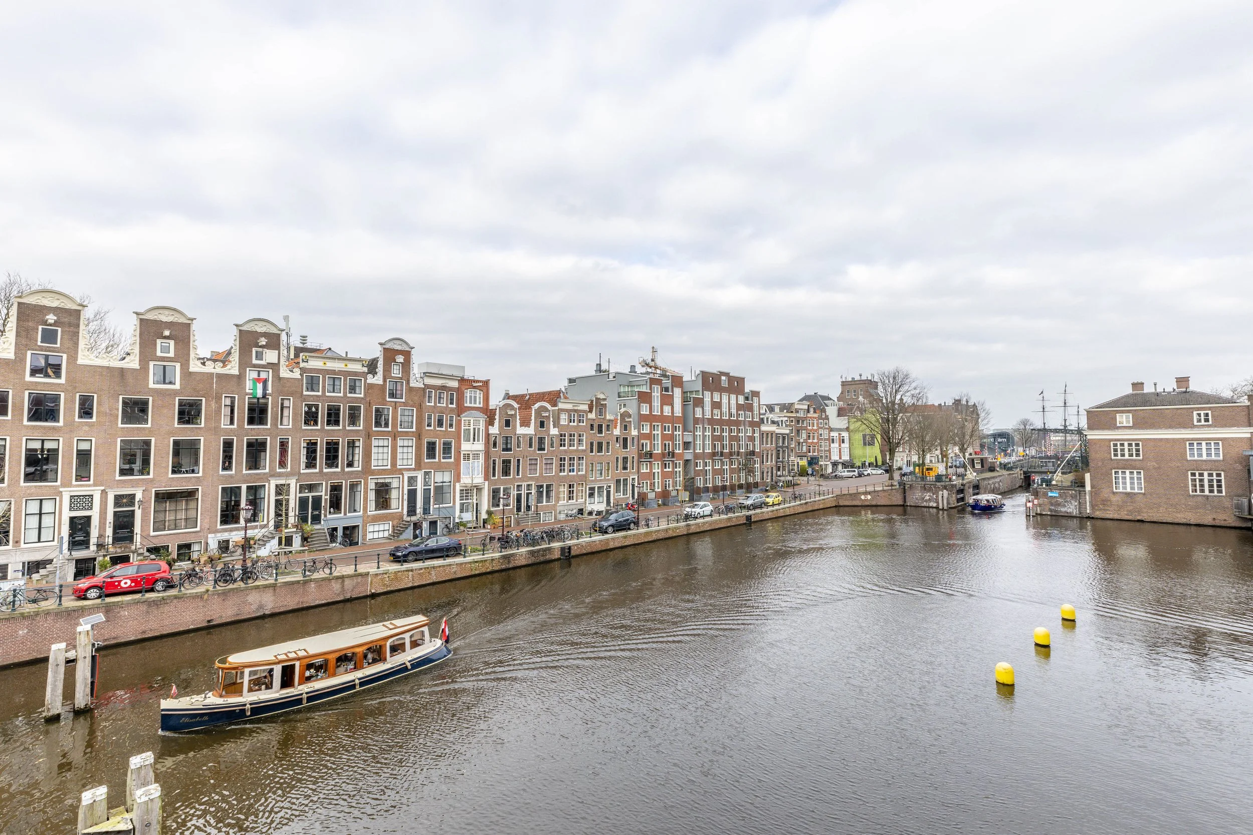 Gezicht op een waterweg met een boot en historische gebouwen langs de oever, in een stad die mogelijk Amsterdam, Nederland is.