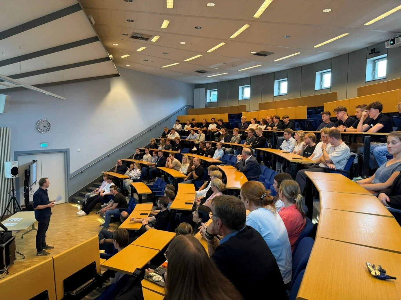 Ein Referent steht vorne im Hörsaal der IBS Oldenburg und spricht vor voll besetzten Sitzreihen mit aufmerksamen Studierenden während der Begrüßungsveranstaltung.