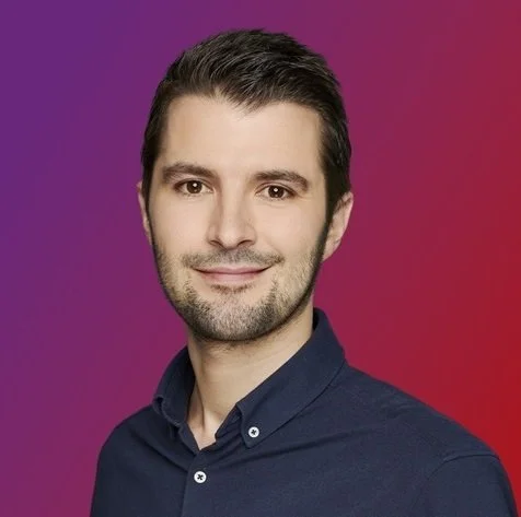 Porträtaufnahme von Andreas Hillebrand, Experte für Erneuerbare Energien bei enercity. Er blickt lächelnd in die Kamera vor einem violett-roten Hintergrundverlauf.