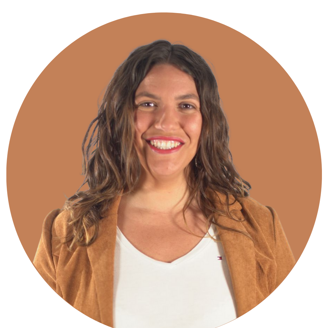 Portrait d'une femme souriante avec des cheveux longs ondulés portant une veste marron et un t-shirt blanc.