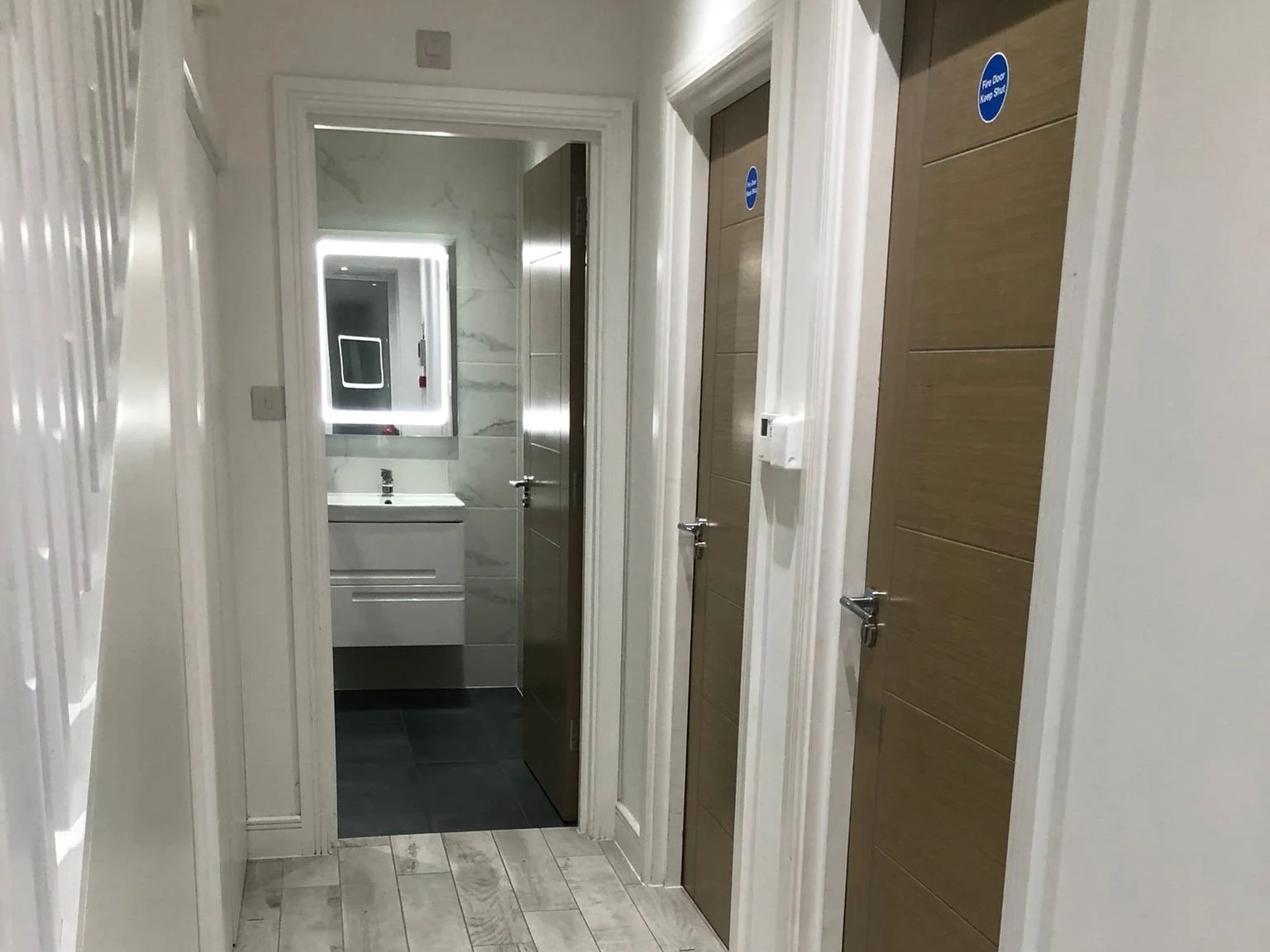 Modern kitchen with white cabinets, black countertop, skylight, and dining chairs.