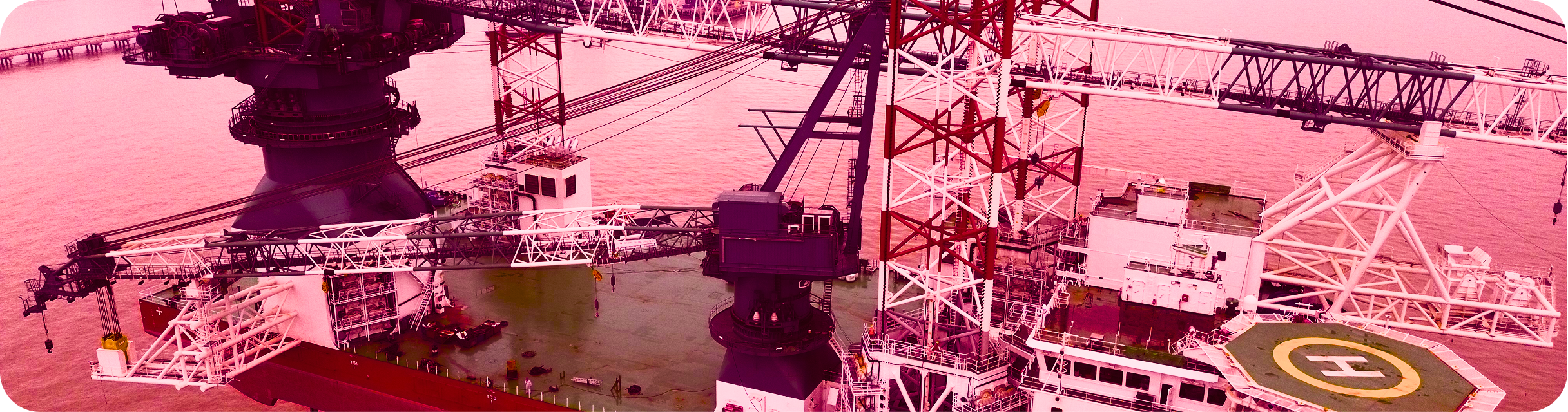 A large offshore oil drilling platform at sea with a helipad and complex machinery, painted in shades of pink and purple.
