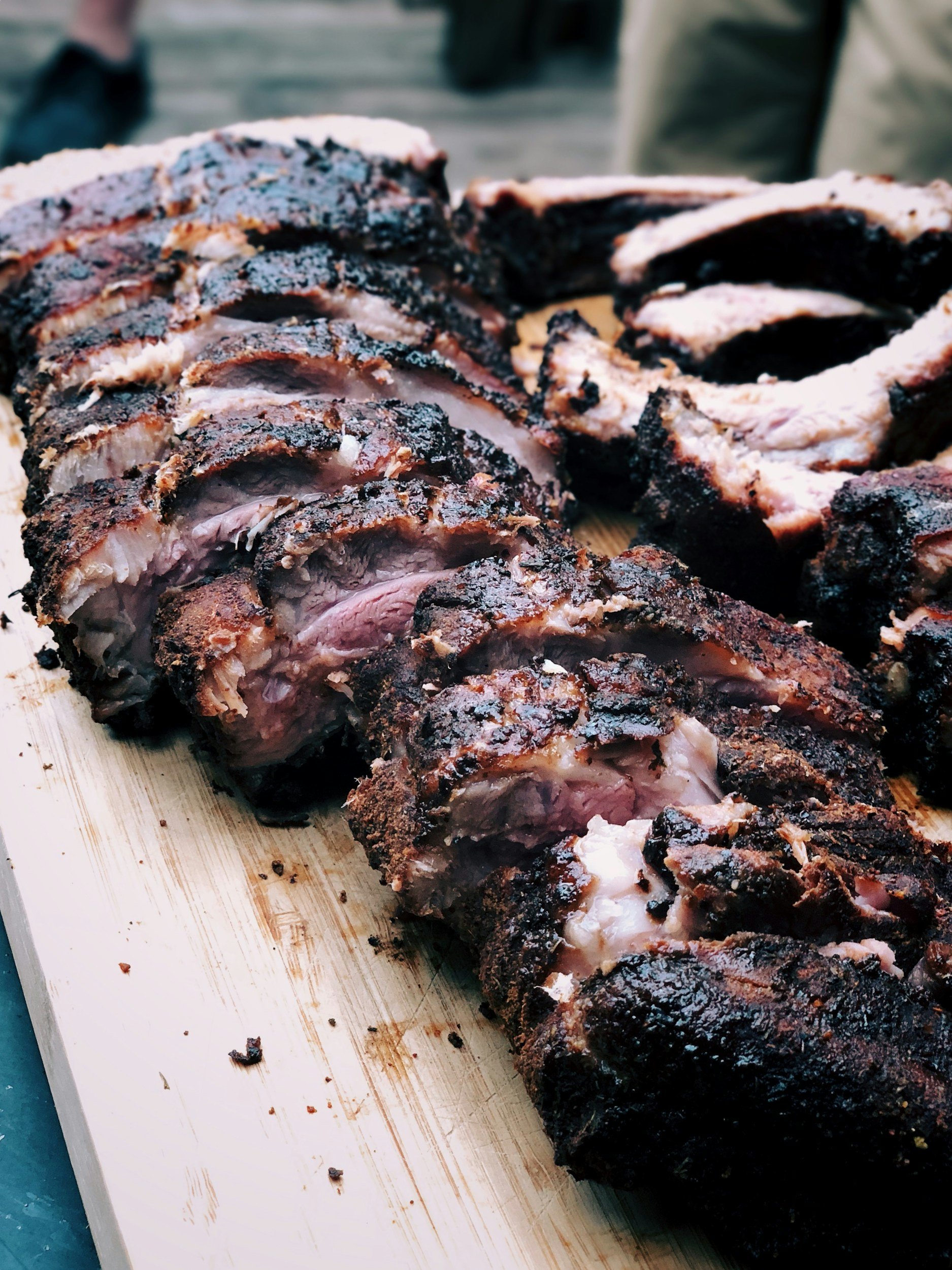 Slices of smoked or grilled meat, likely brisket, on a wooden cutting board.