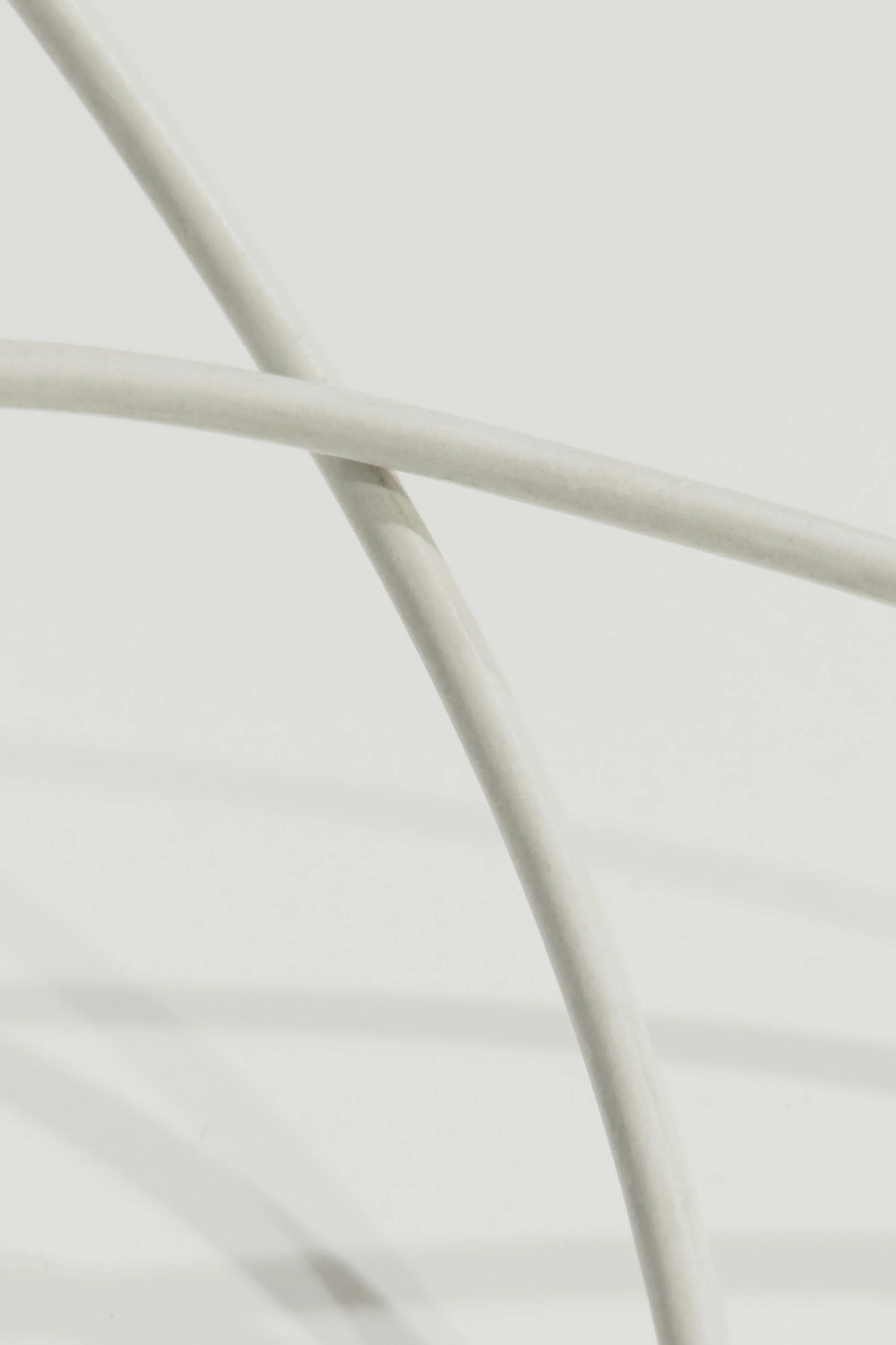 Two white curved rods intersecting and casting soft shadows.