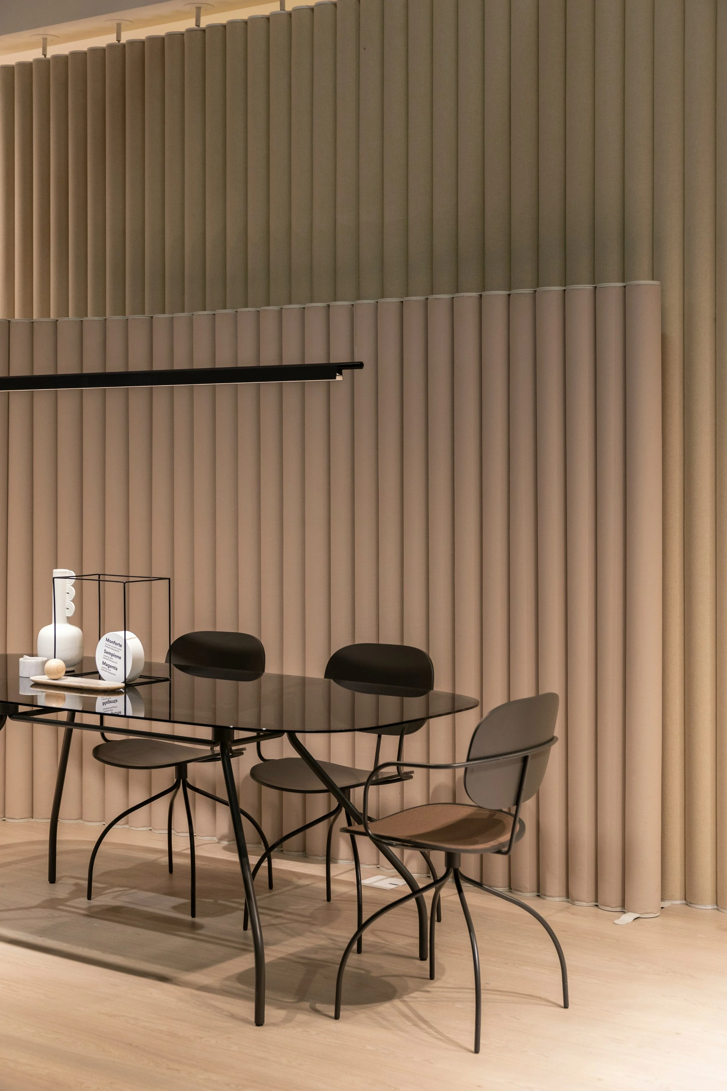 Oval glass table surrounded by armchairs in a softly lit meeting room.