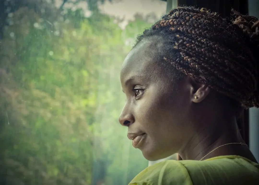 Woman looking thoughtfully out a window, reflecting self-trust and learning to understand anxiety and intuition.