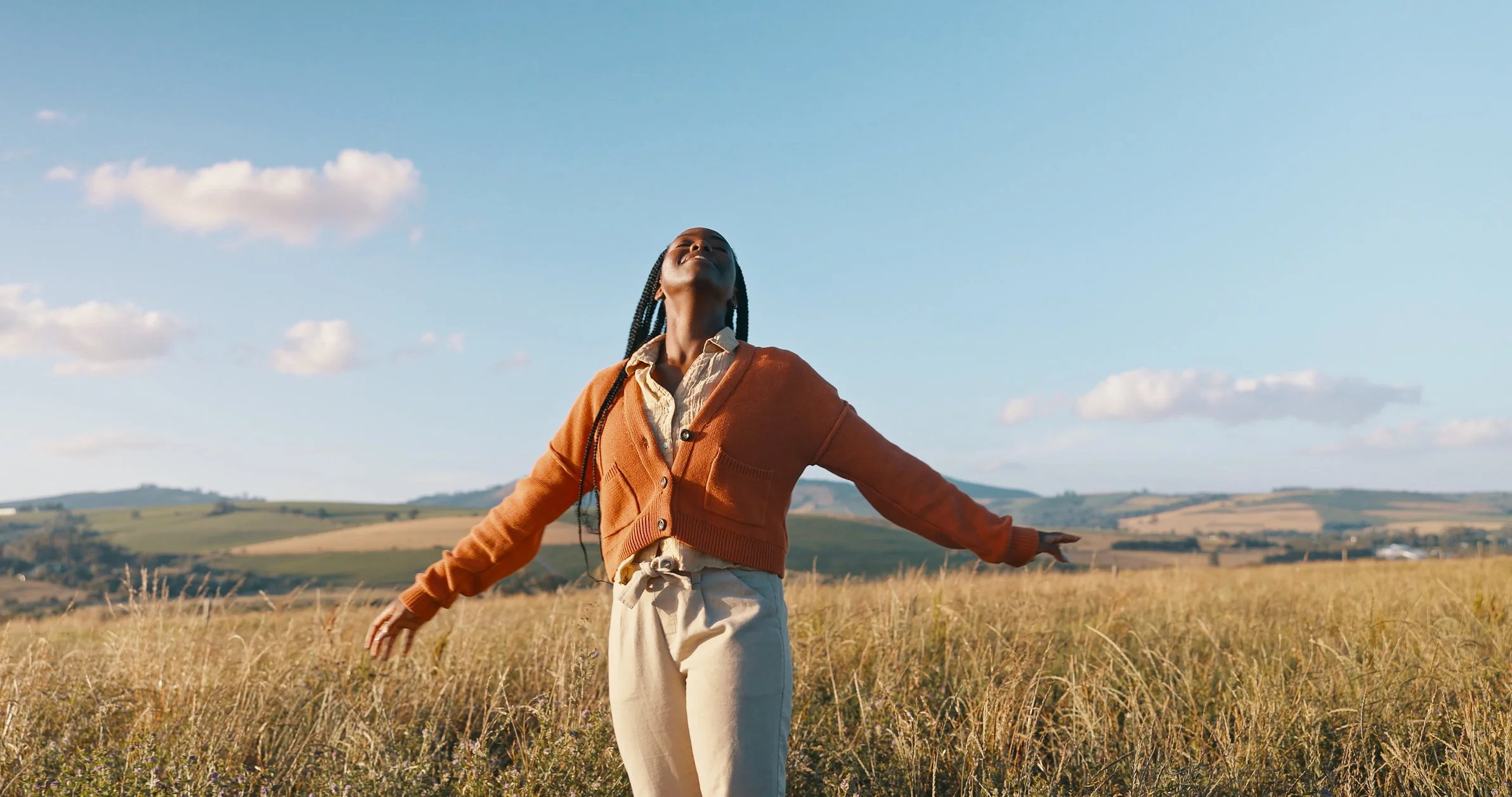 Person with open arms in a sunlit field, illustrating confidence and the emotional growth supported by self-esteem therapy.