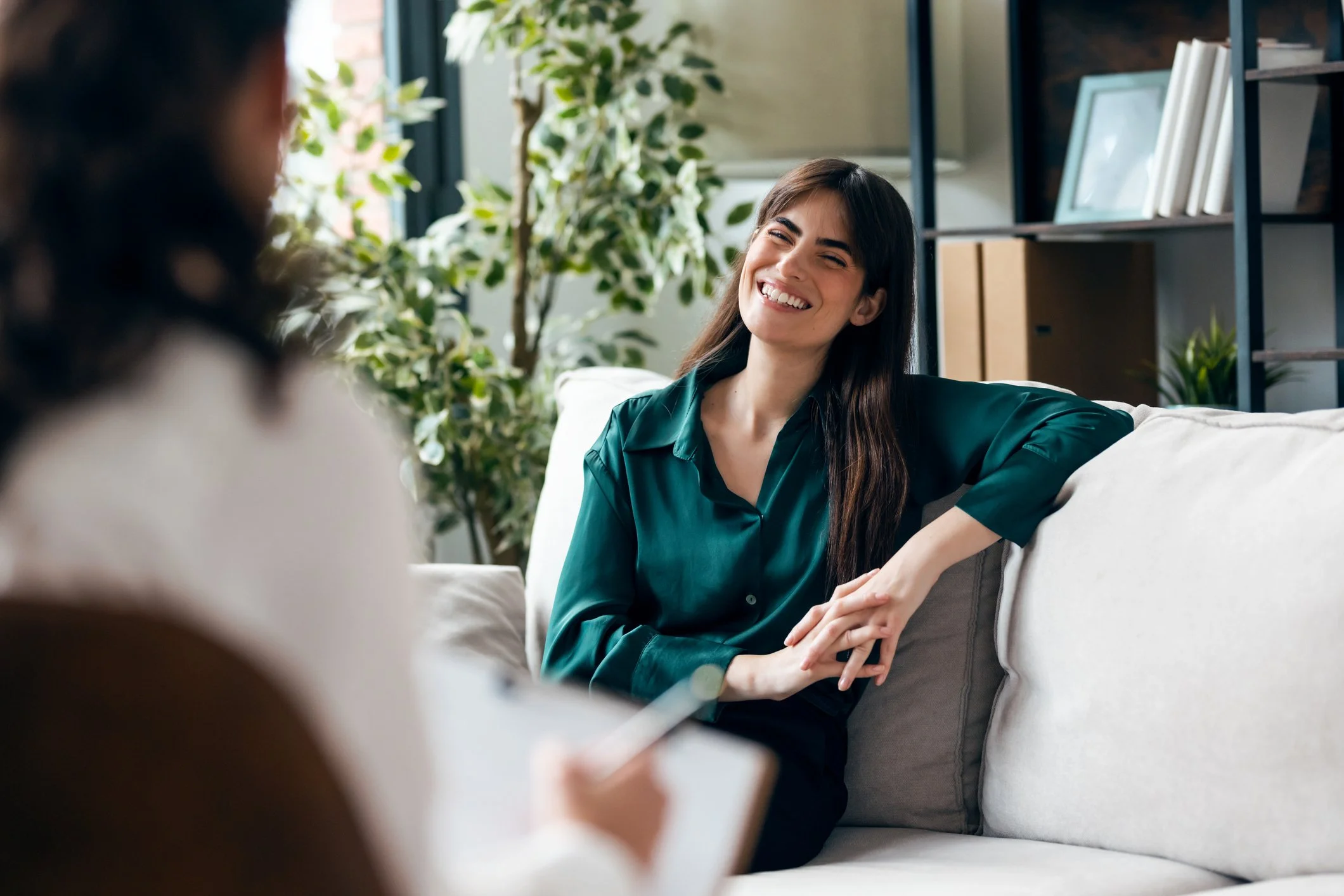 Woman smiling while speaking with a therapist in a bright counseling office.