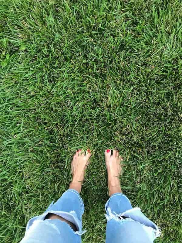 Bare feet standing in green grass, representing grounding and reconnecting with the body through the nervous system.