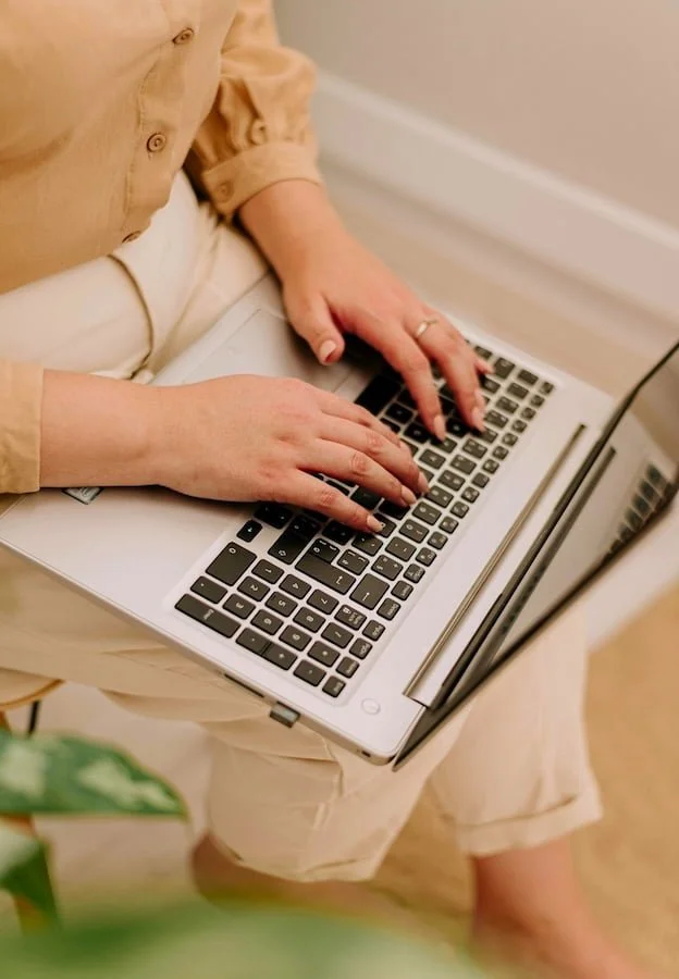 Woman seated with a laptop resting on her lap.